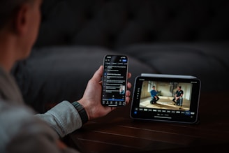 Person holding phone and looking at monitor