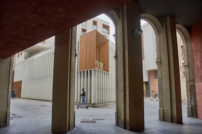 Person riding scooter through modern architectural arcade