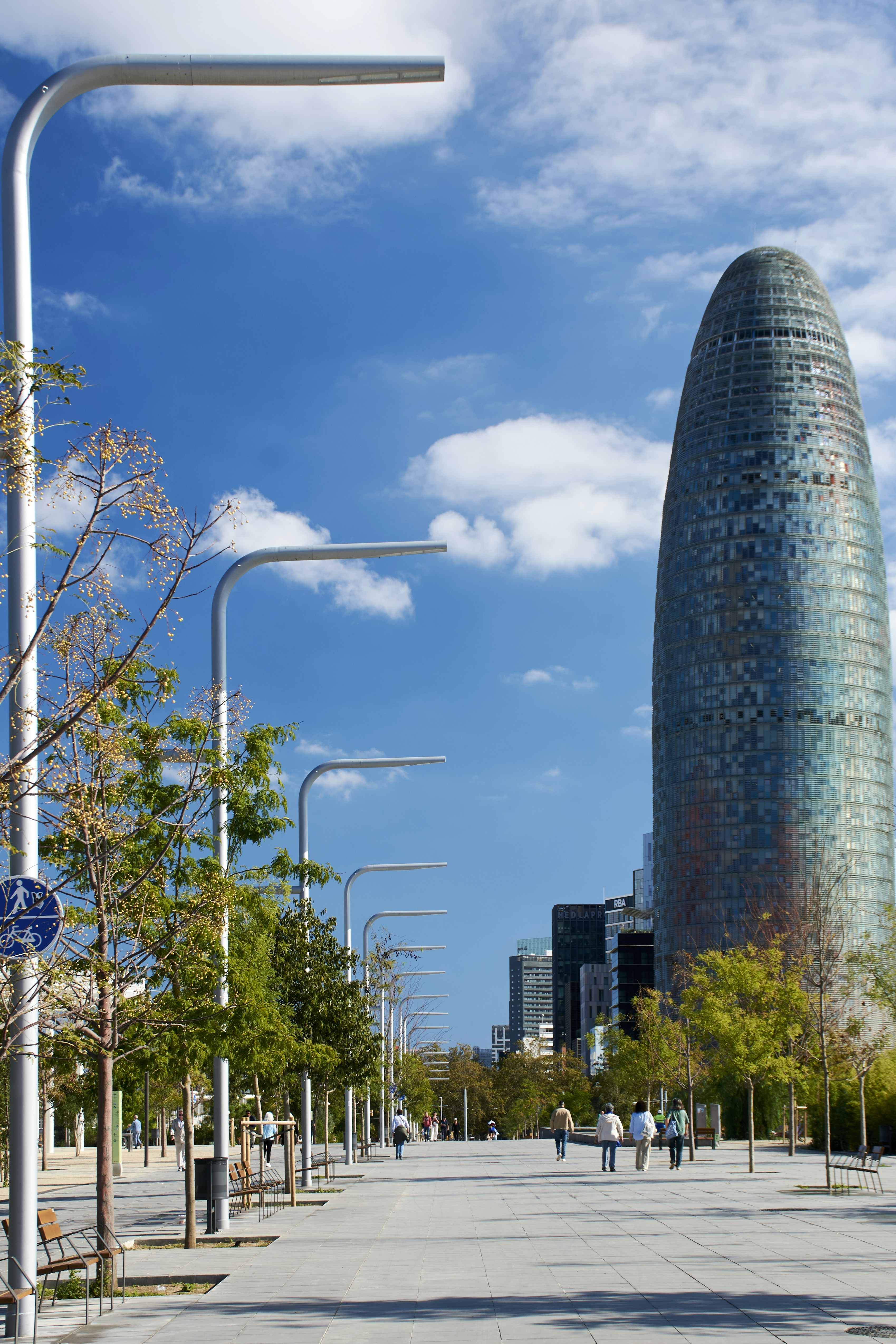 Modern skyscraper and tree-lined promenade under blue sky