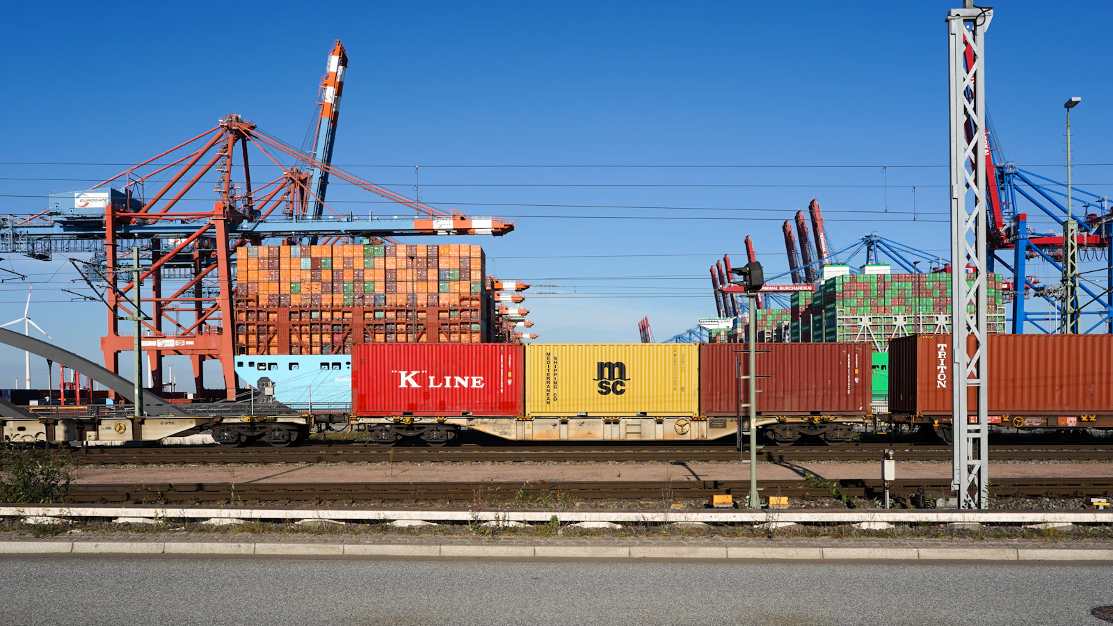 Freight train loaded with shipping containers moving through an industrial terminal