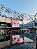 Modern waterfront shopping complex with large digital billboards.