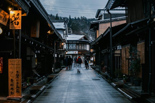 People walk down a snowy street in a historic town — Takayama, Japan