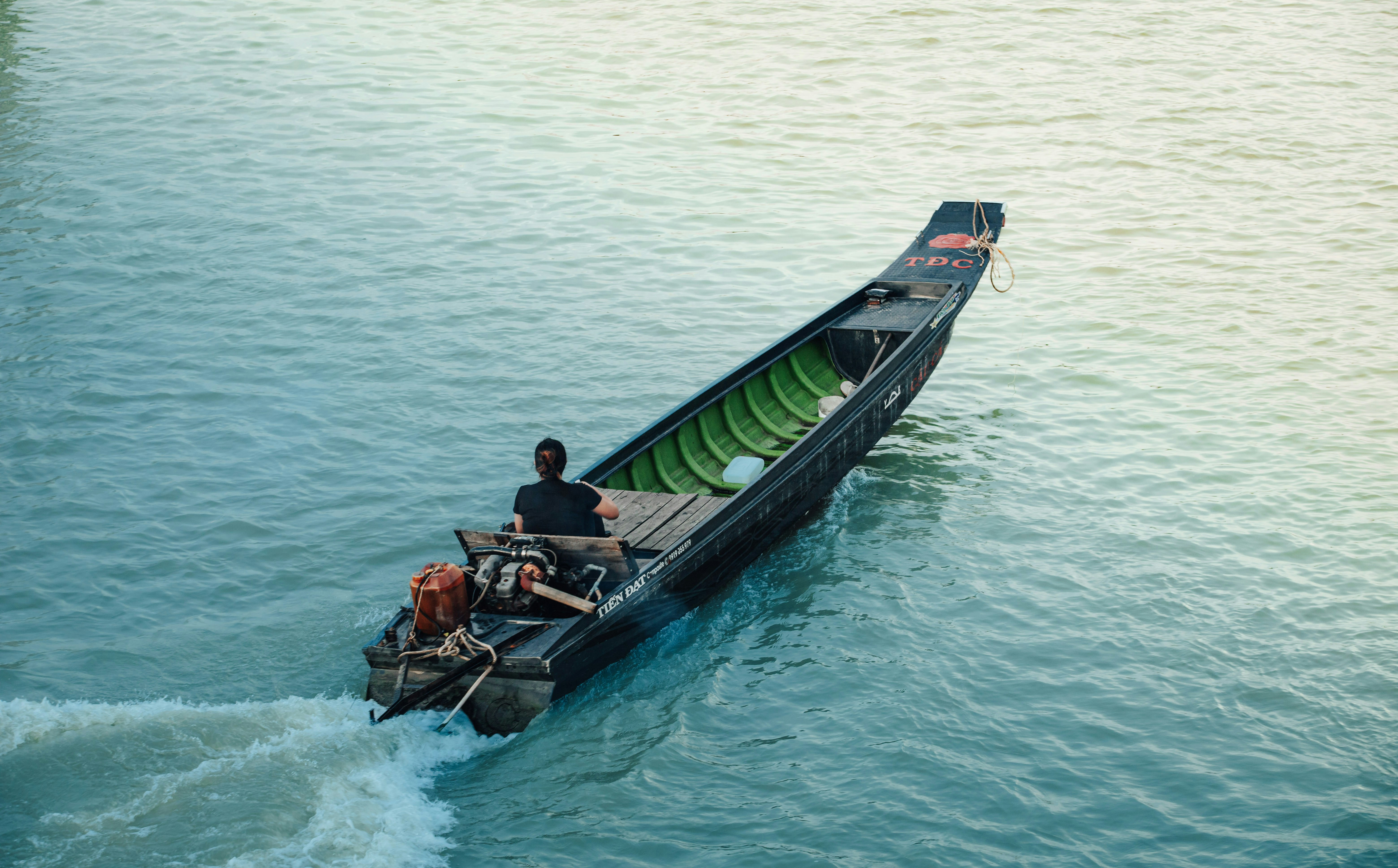 Homme conduisant une longue embarcation sur une eau turquoise