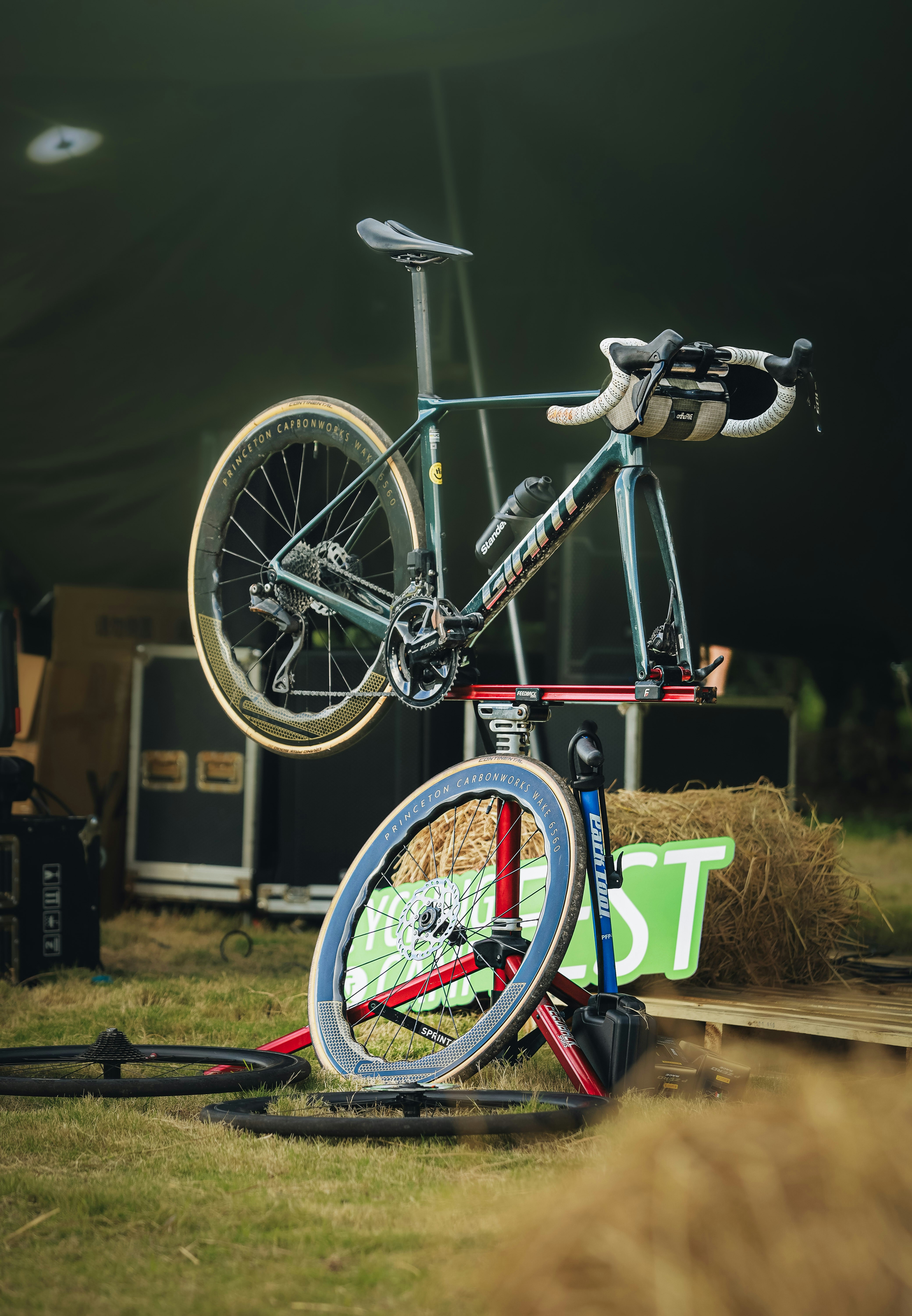 A bicycle is being repaired on a stand outdoors.