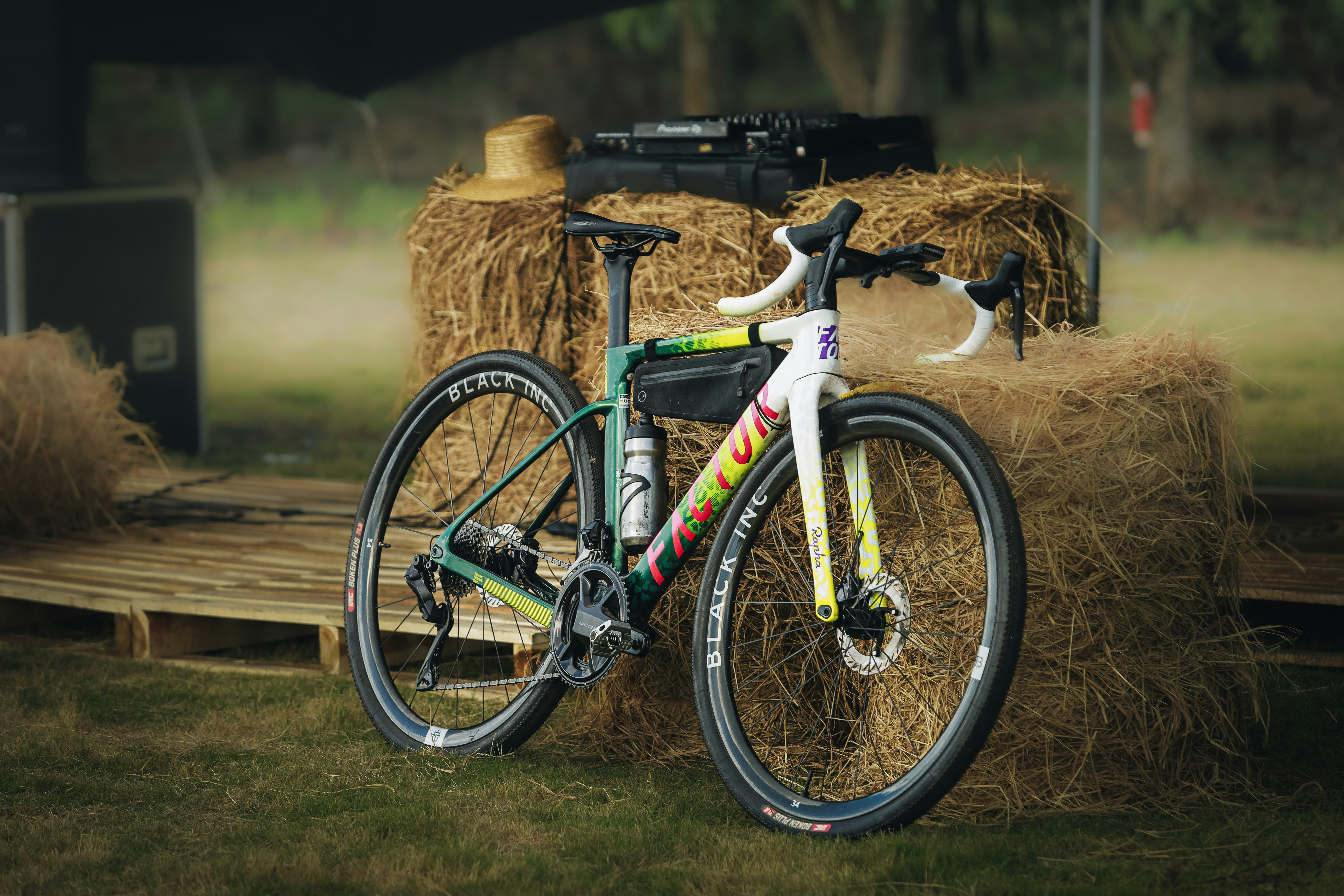 A colorful gravel bike rests against hay bales.