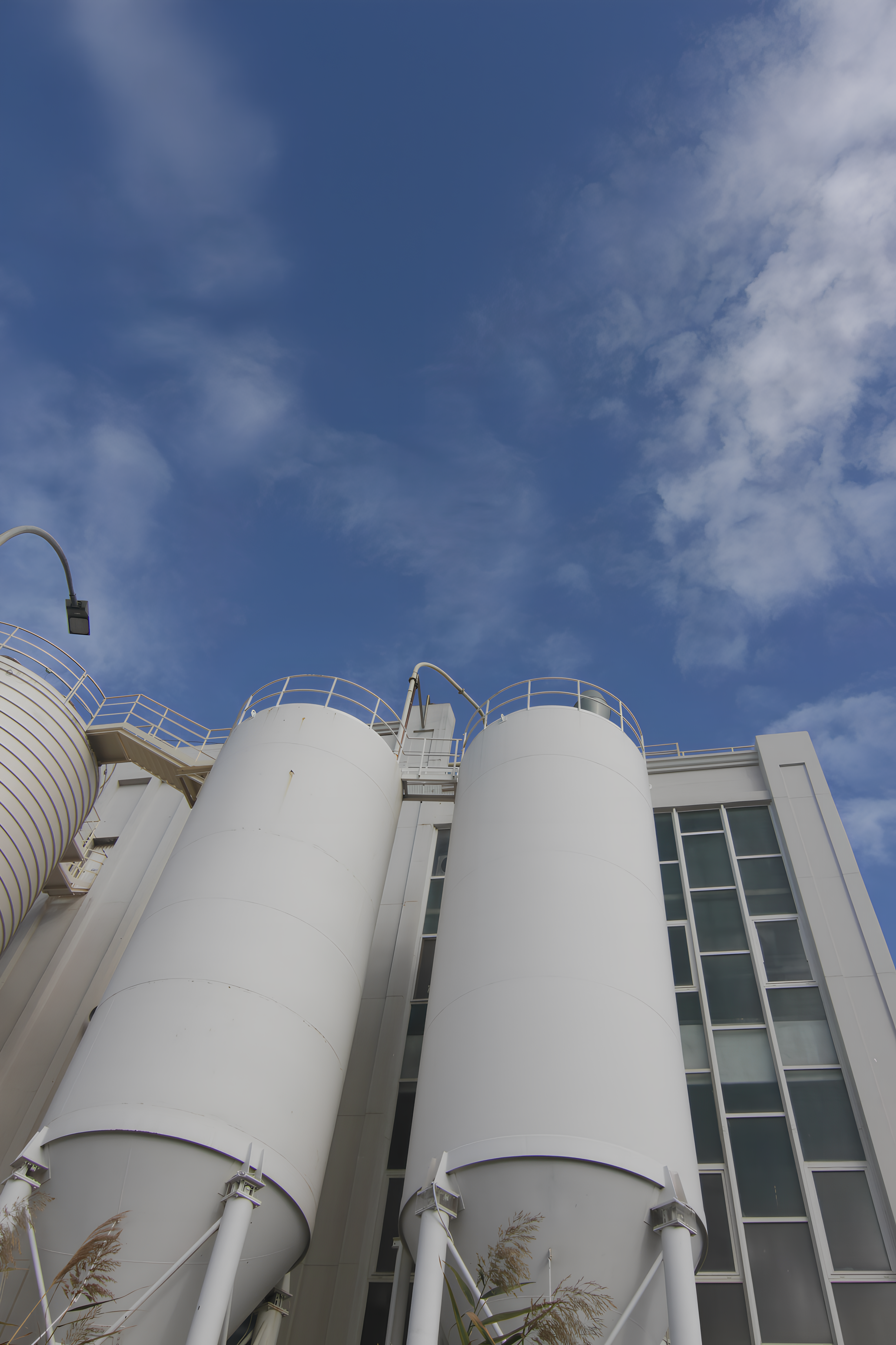 Zwei weiße Industriesilos vor einem blauen Himmel.