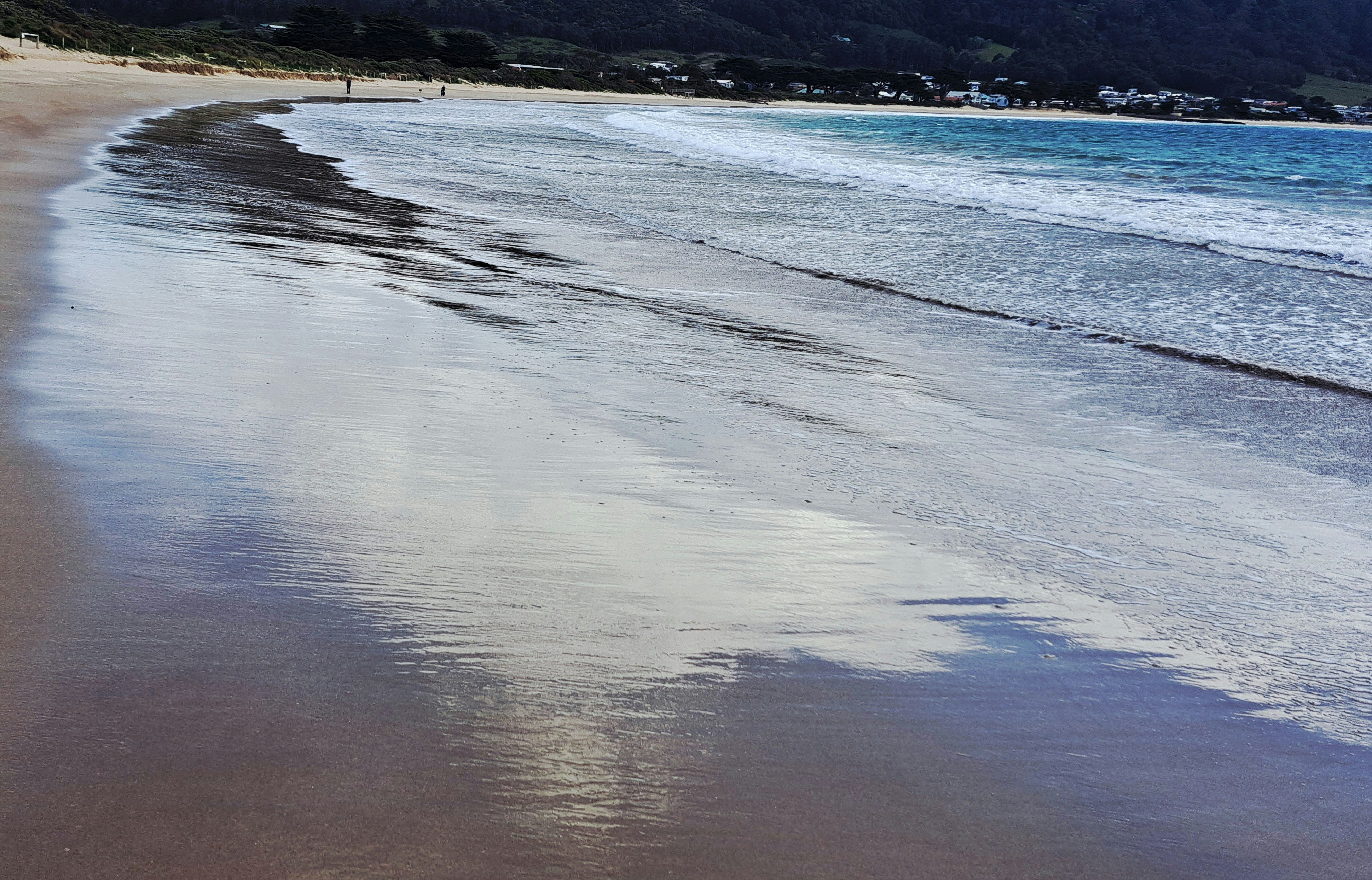 Wet sand reflecting the sky and ocean waves