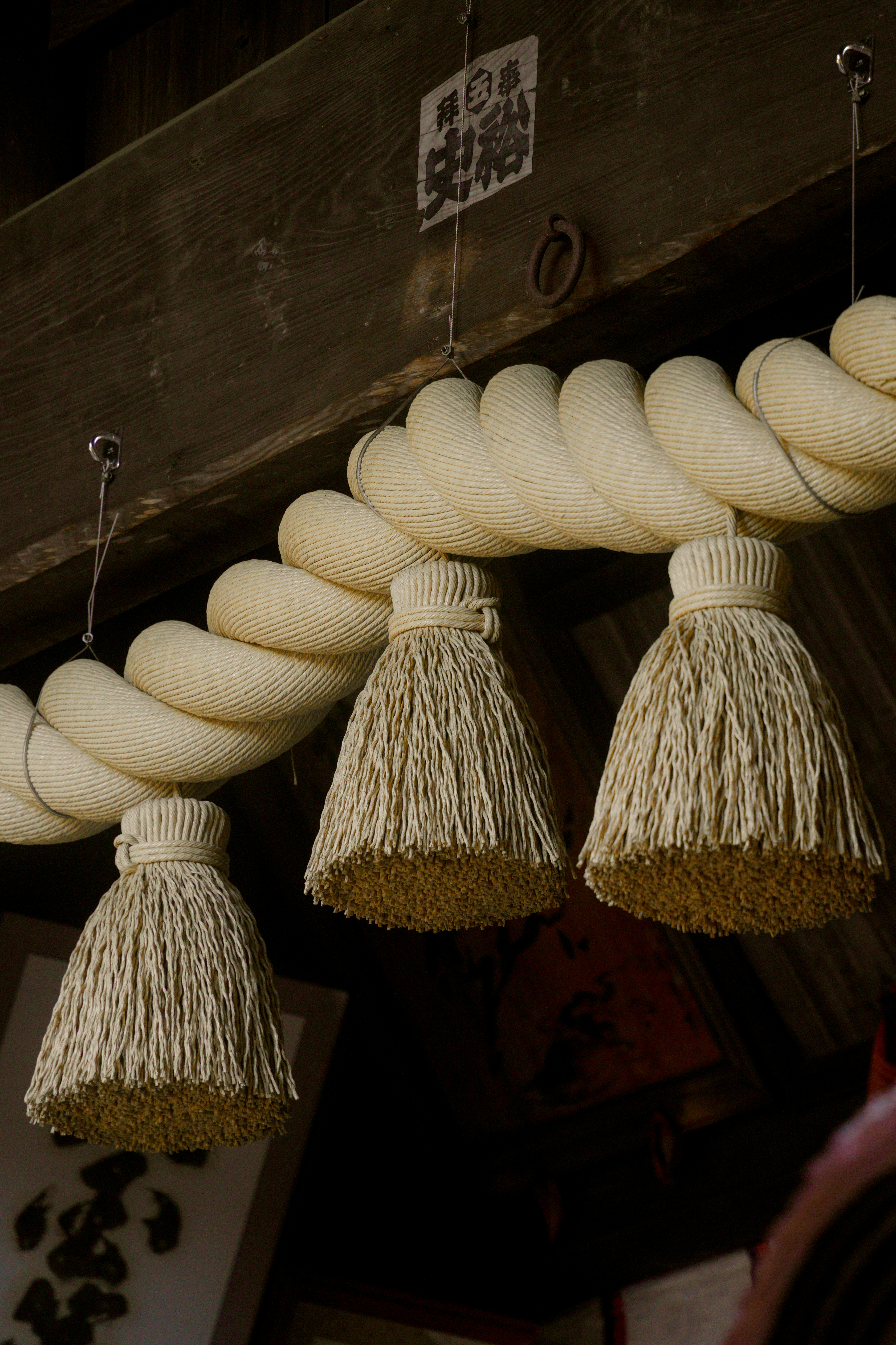 Three straw ornaments hang from a thick rope.