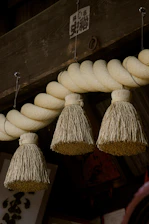 Three straw ornaments hang from a thick rope.