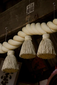 Three straw ornaments hang from a thick rope.