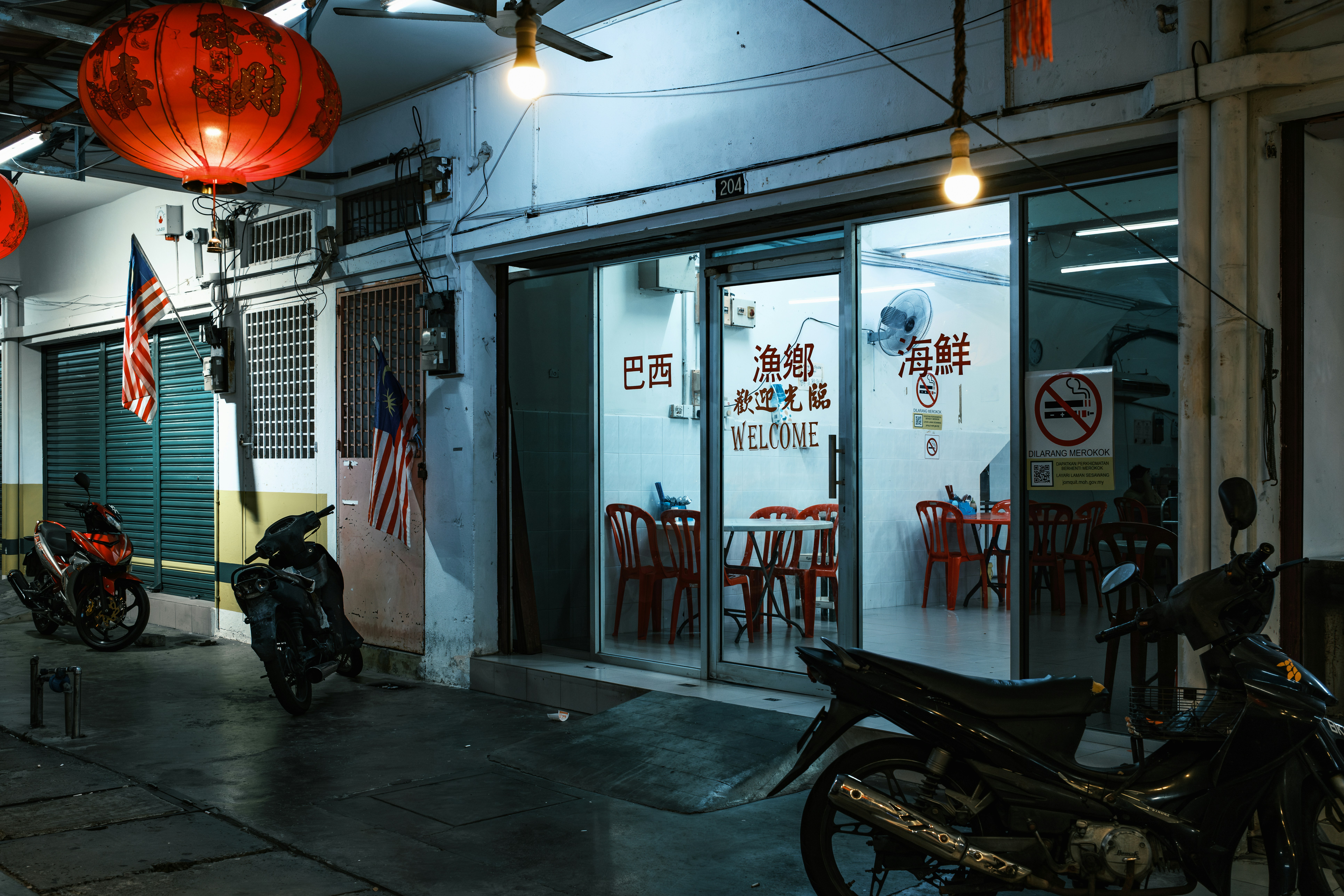 Street scene with red lanterns and parked motorcycles at night.