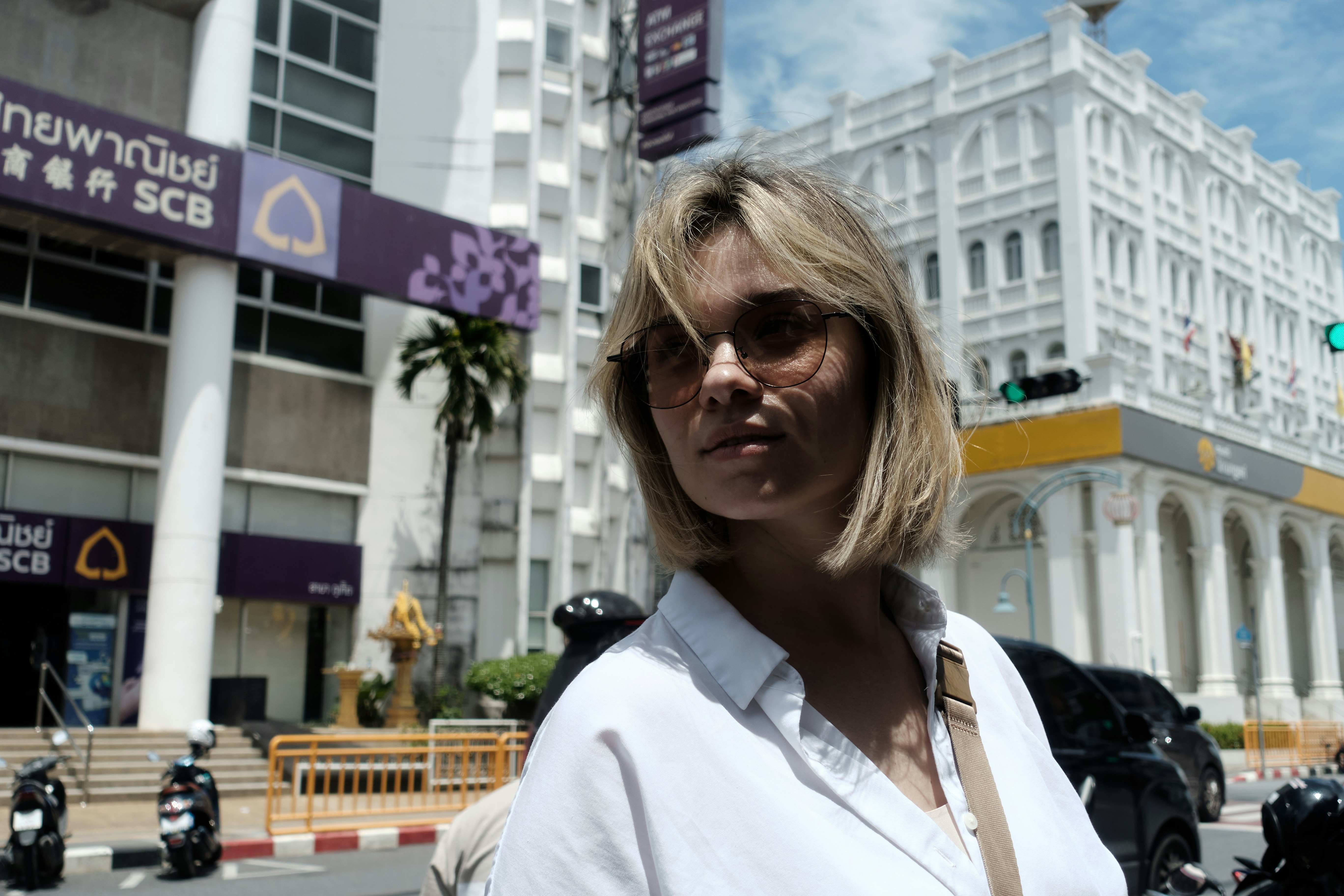 Blonde woman in sunglasses in front of bank