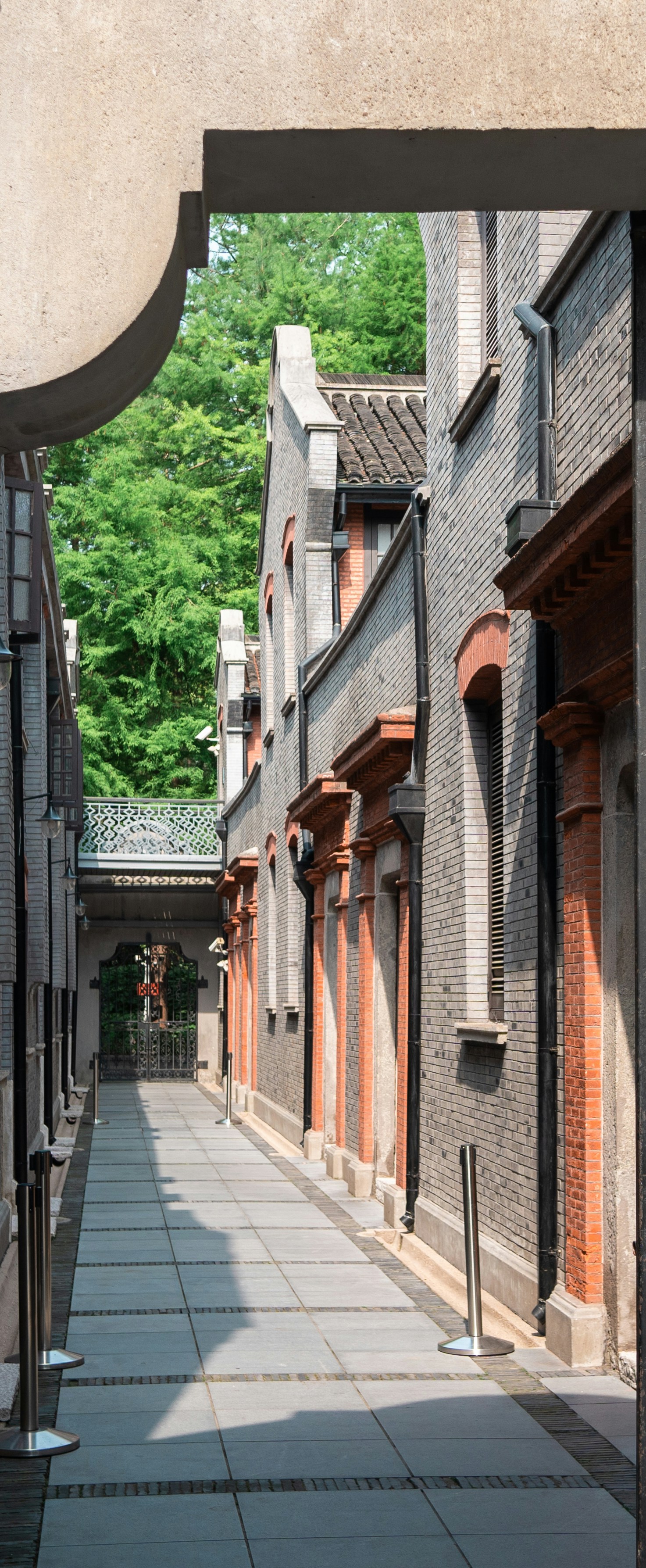 Narrow alleyway between old brick buildings with trees.