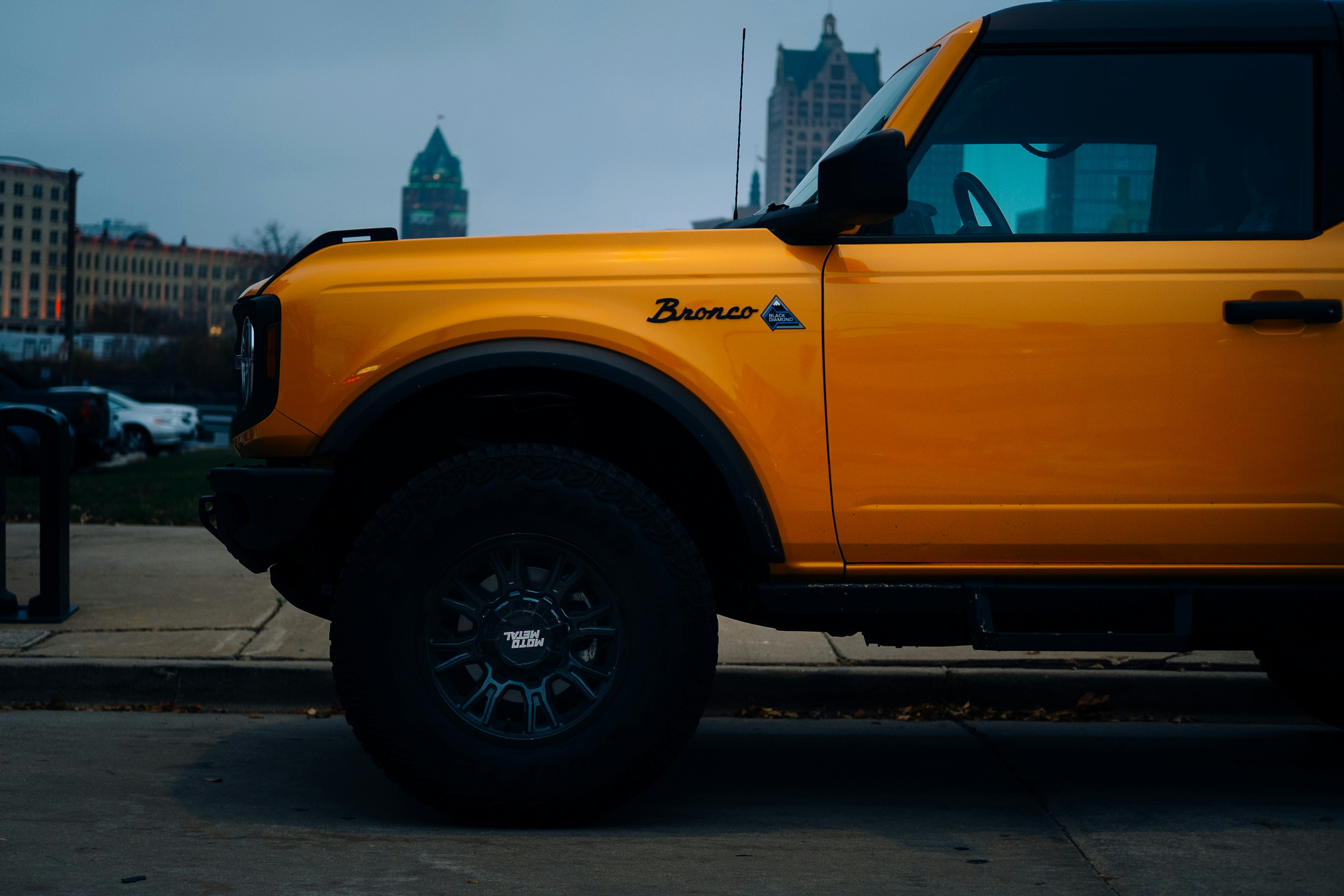 黄色いフォード・ブロンコが市街地の通りに駐車されている