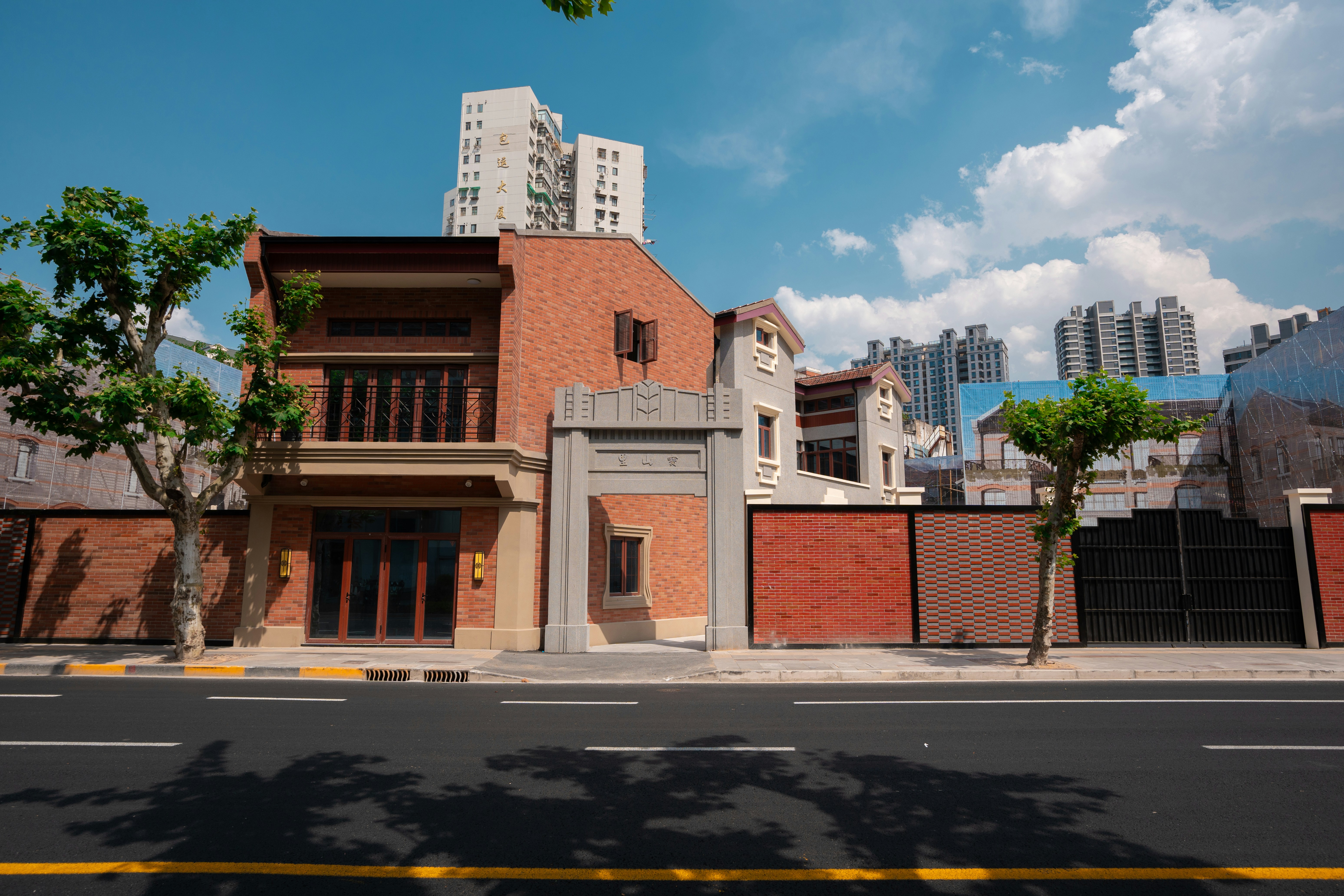 Brick buildings and trees line a sunny street.