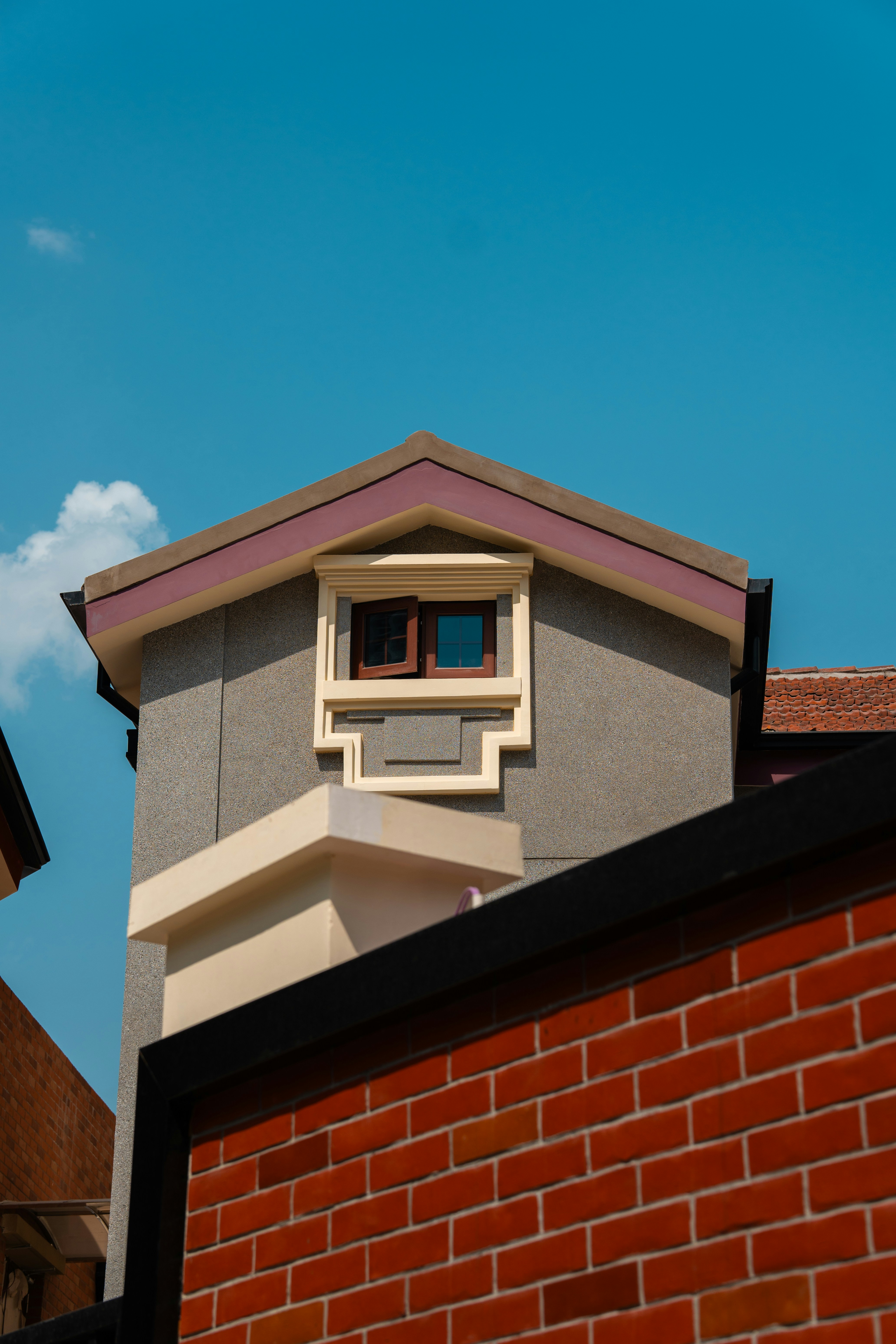 A building with a dormer window against blue sky.