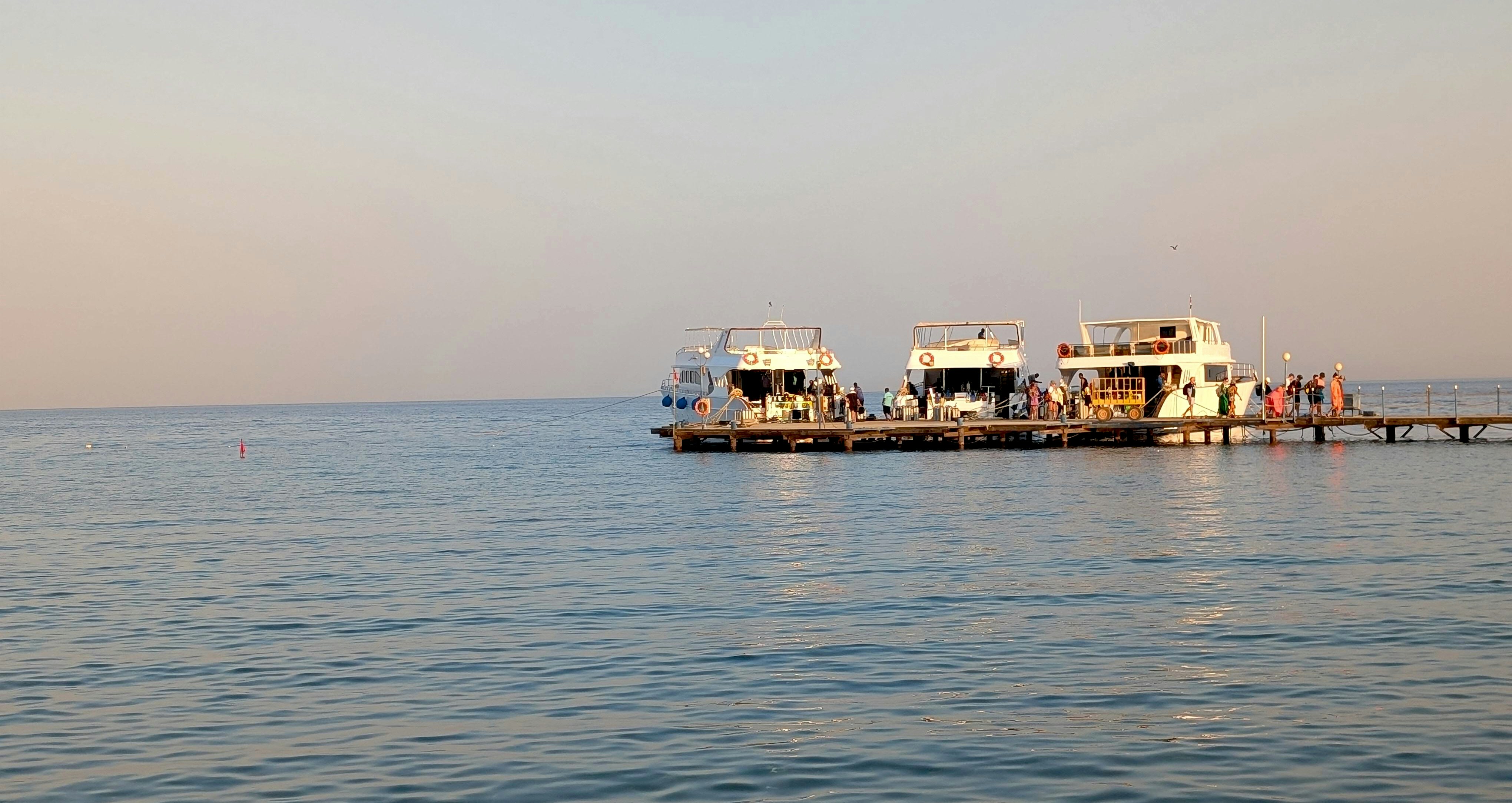 Boats docked at a pier on a calm sea.