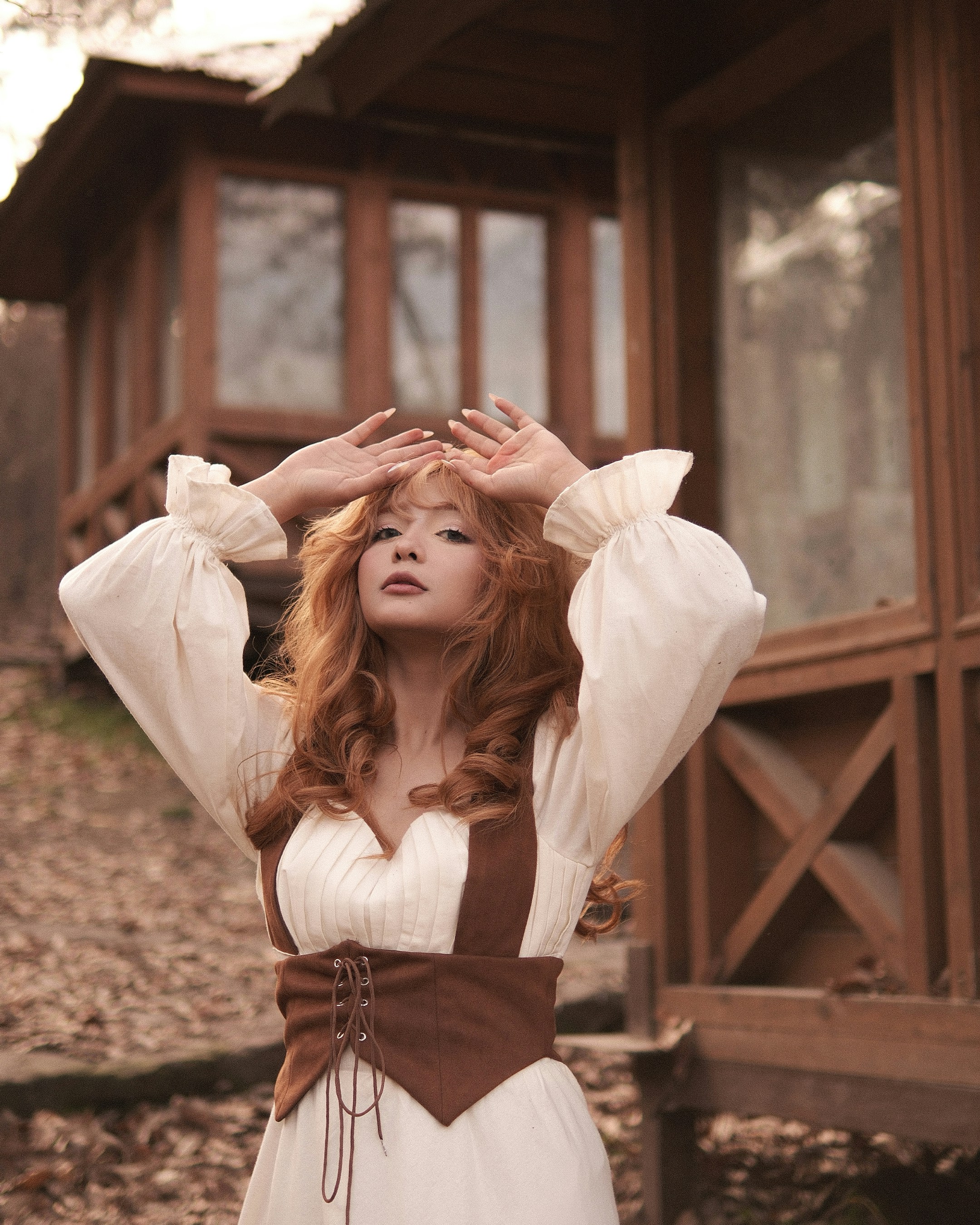 Woman with red hair in a white dress and vest.