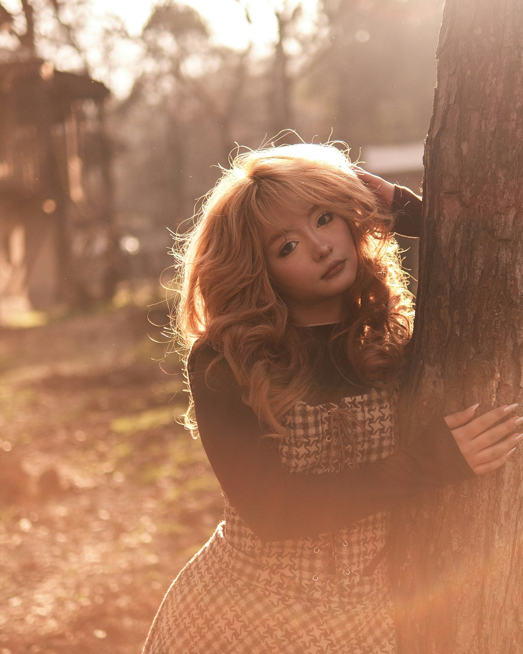 Young woman with blonde hair by a tree