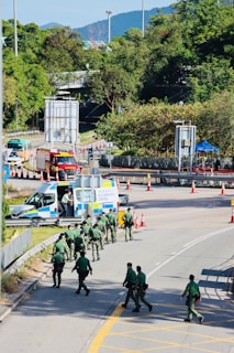 Police officers walk down a street near emergency vehicles.