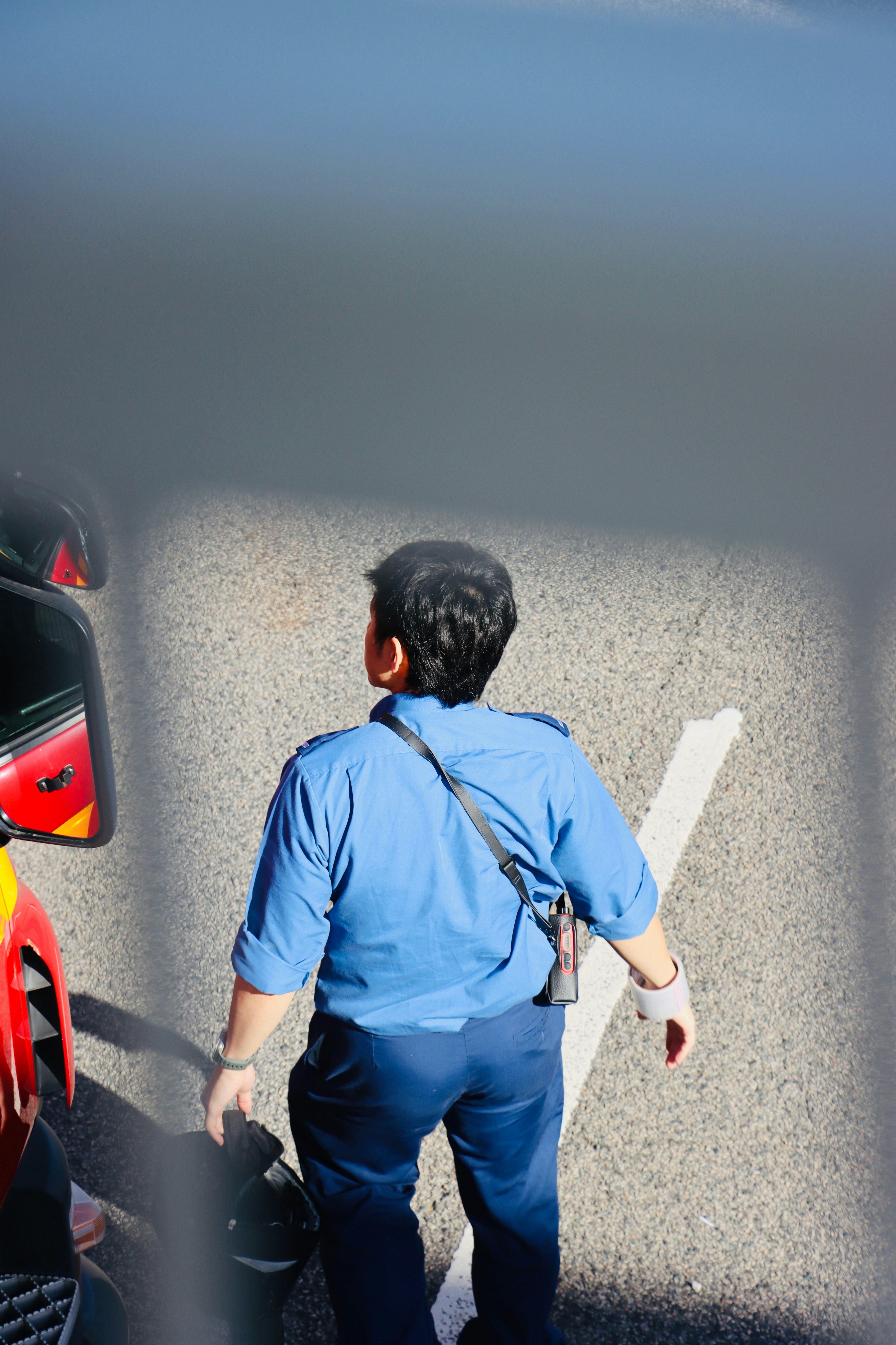 Man in blue shirt standing on asphalt