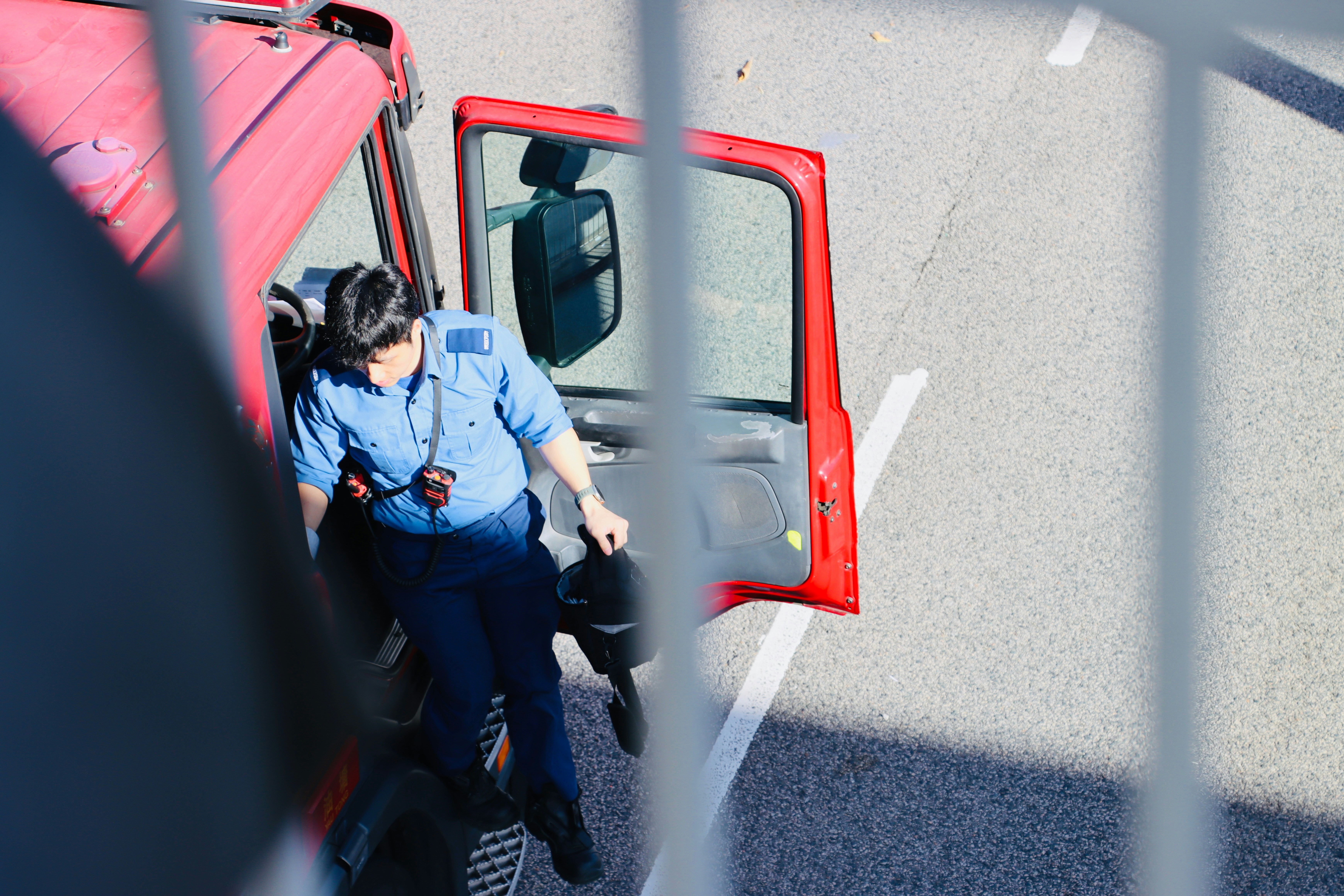 A person in uniform exiting a red truck.