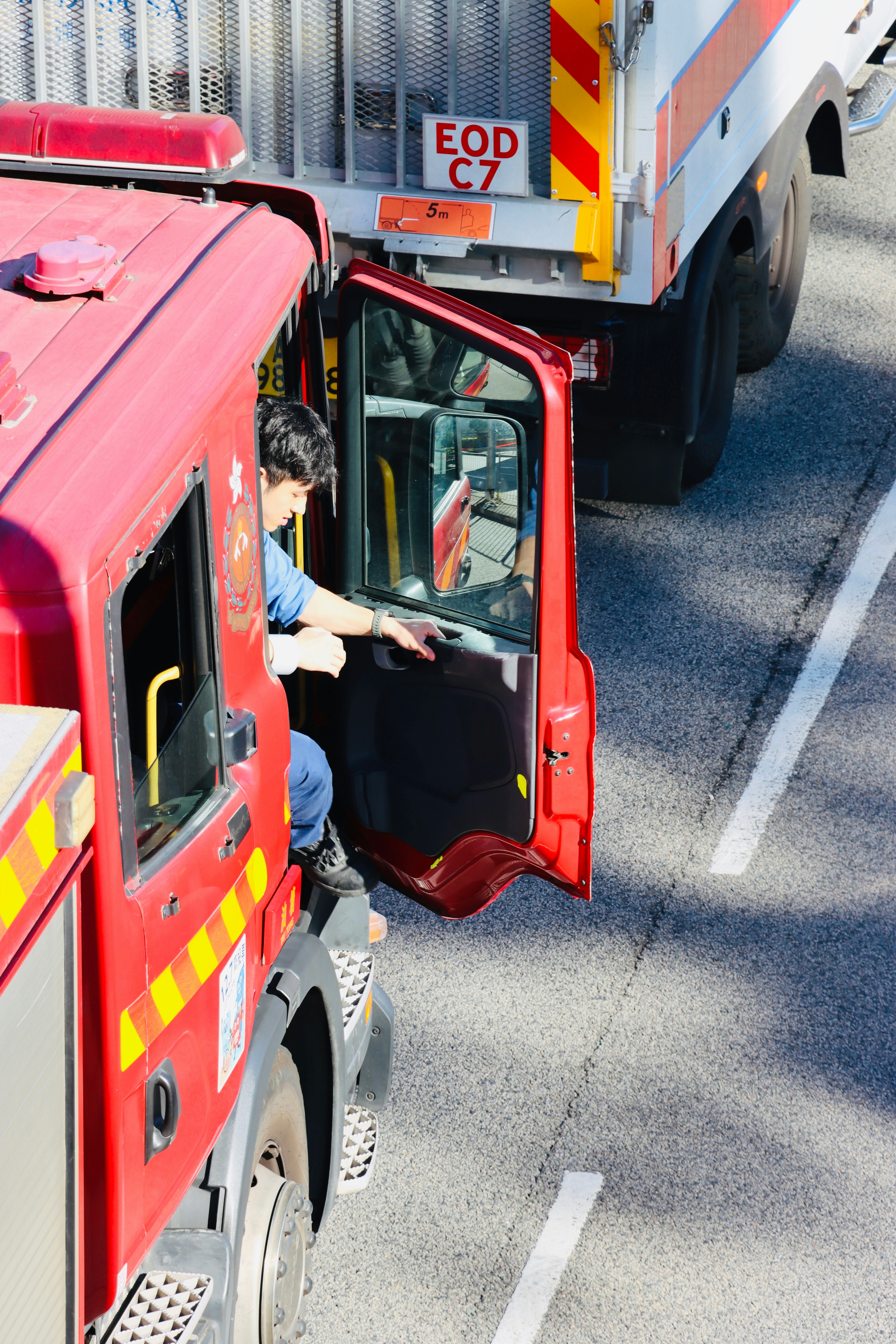 Firefighter exiting a red fire truck on a road
