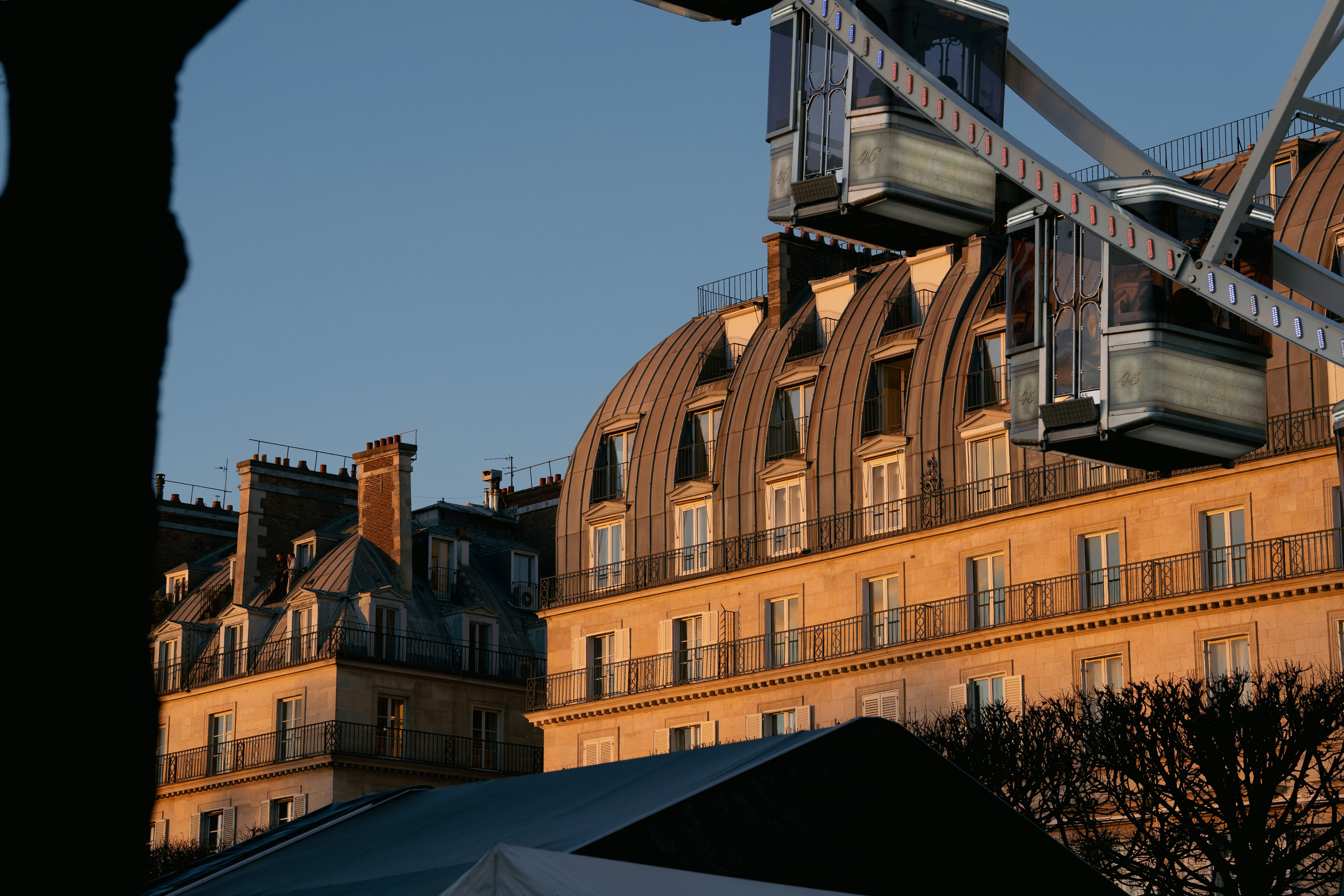 Edifícios parisienses com telhados mansarda ao pôr do sol.