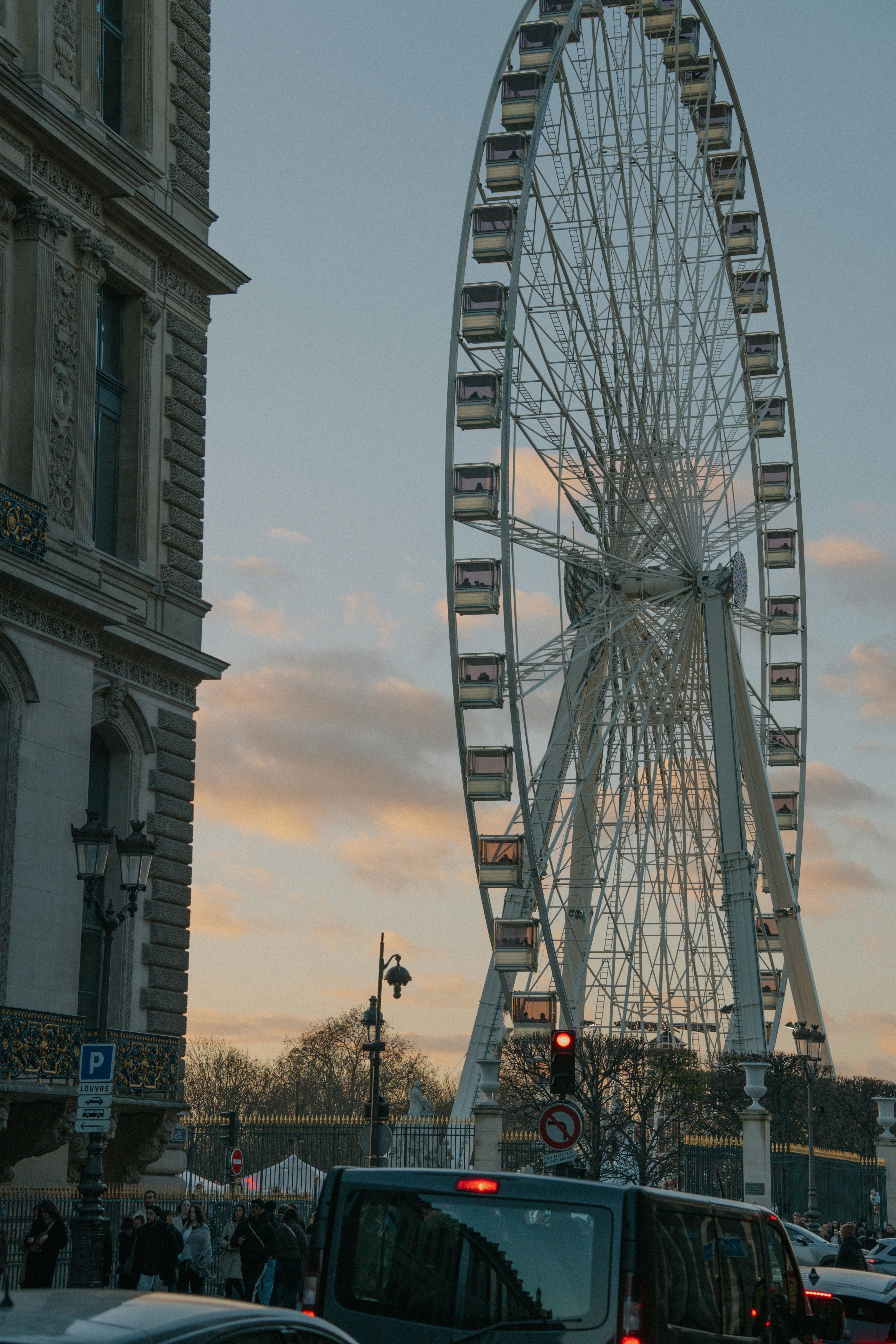 Roda-gigante se erguendo sobre a rua da cidade ao entardecer
