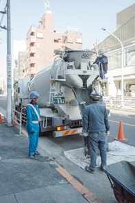 Construction workers near a cement mixer truck.