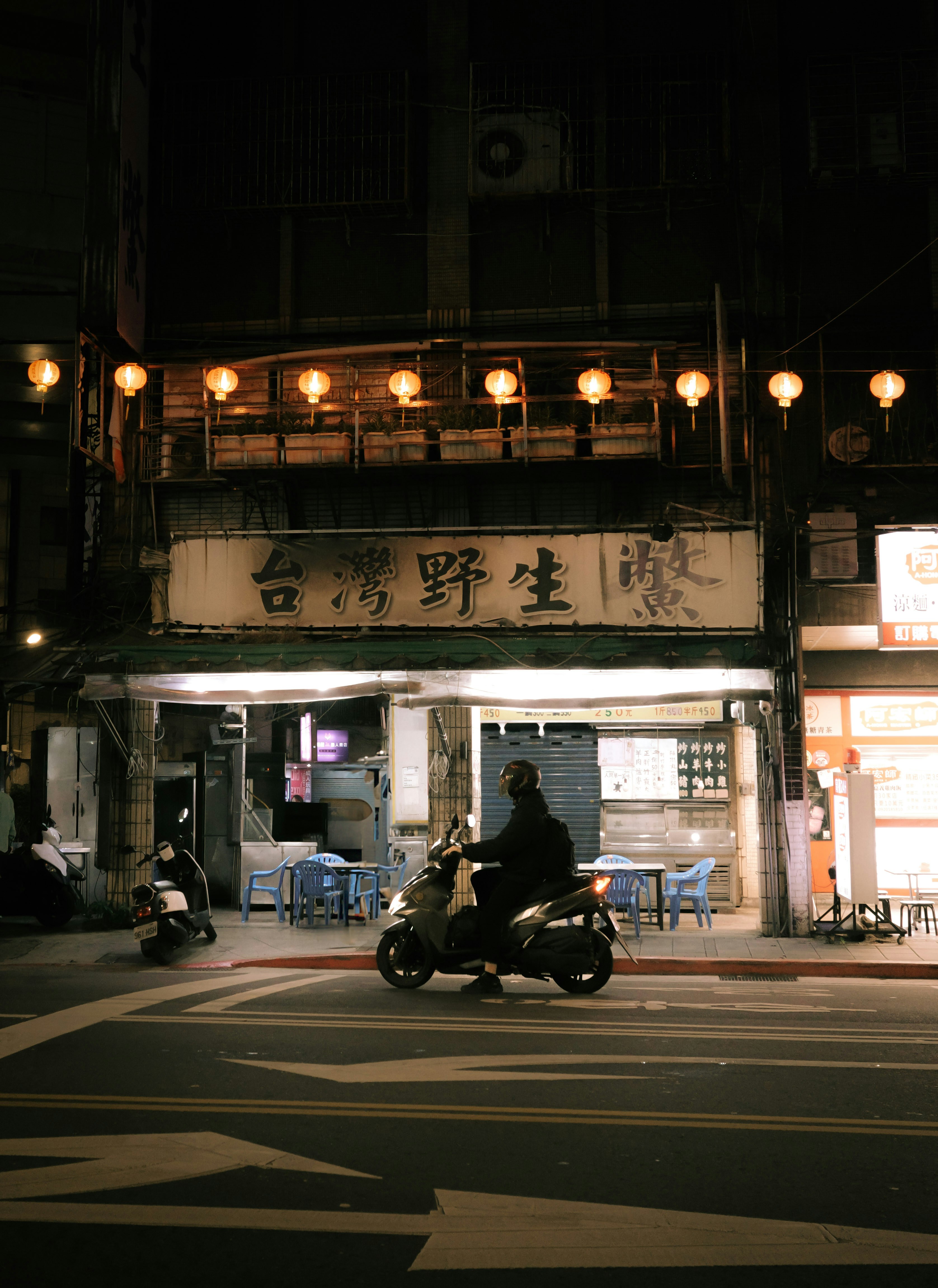 Man rides scooter past storefront at night
