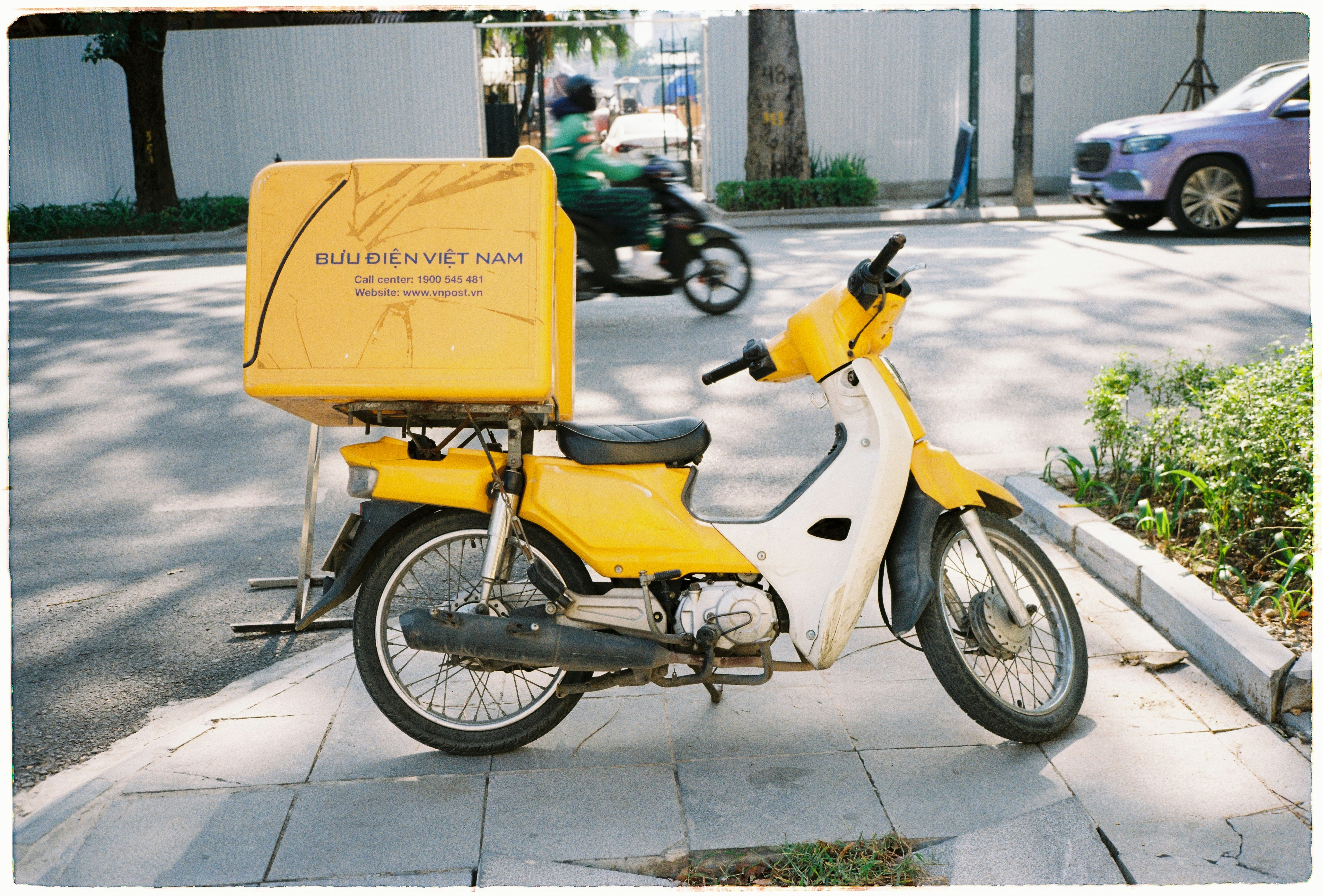 Yellow delivery motorcycle parked on sidewalk