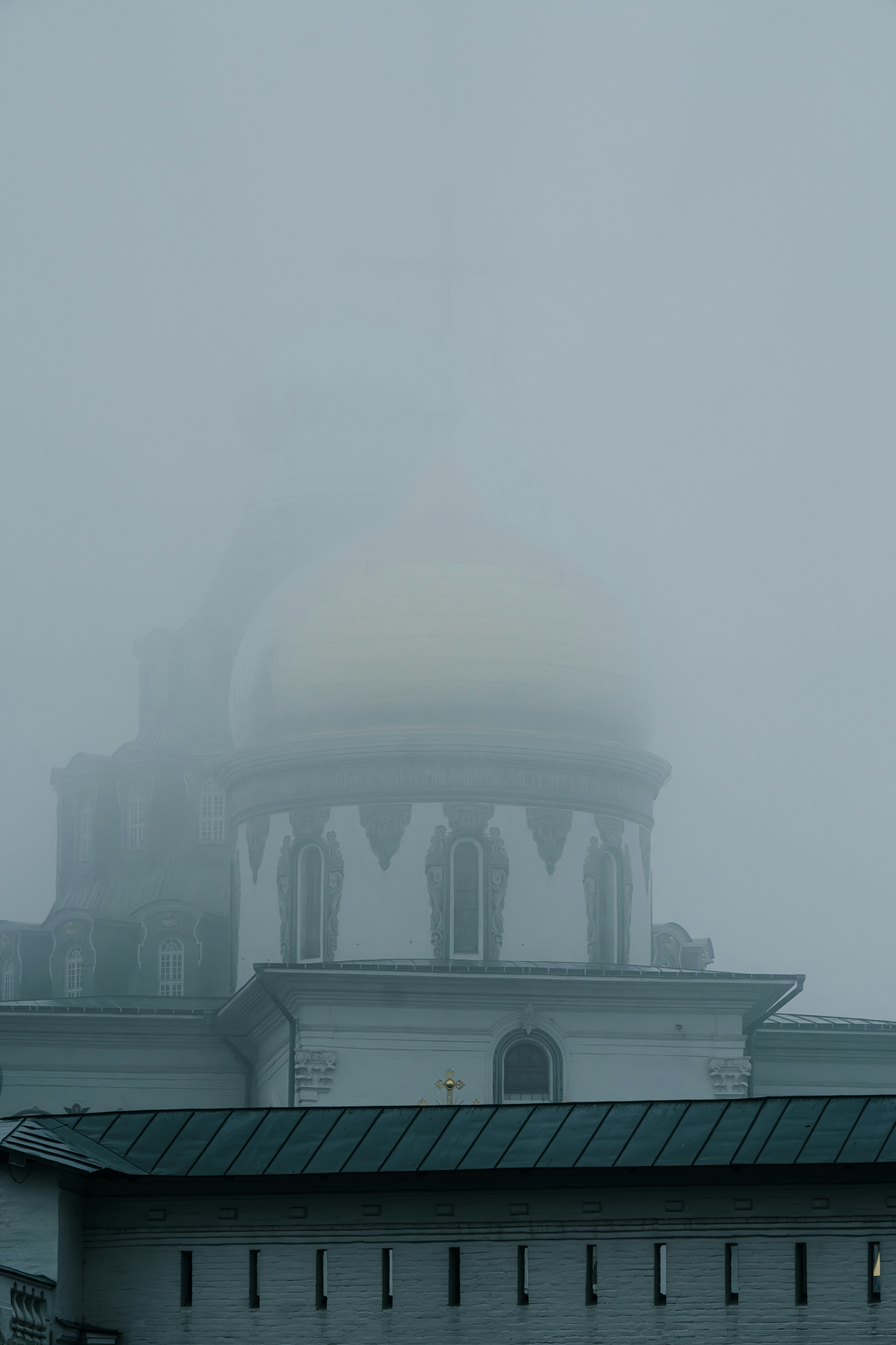 A white building with a dome shrouded in fog.
