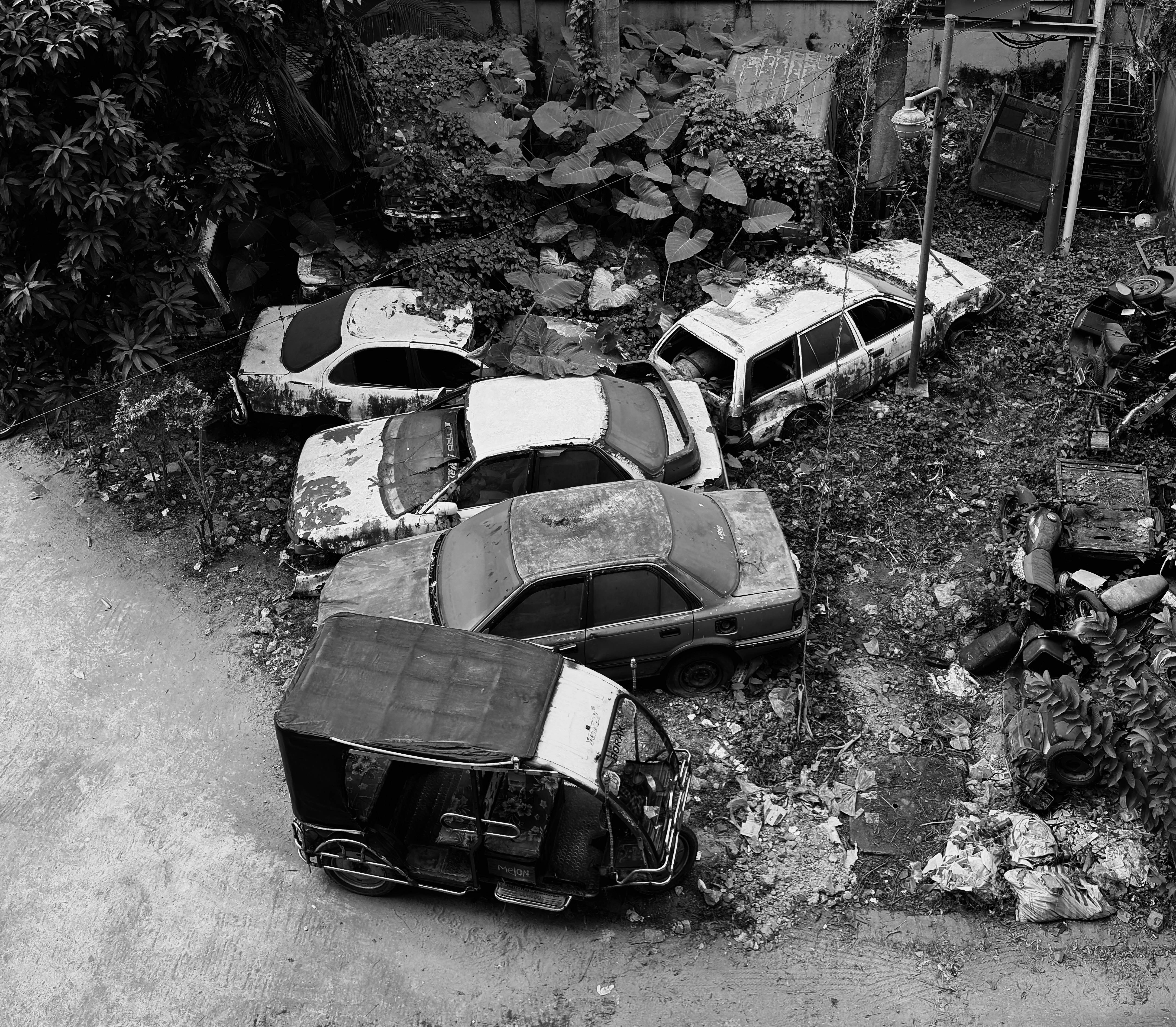 Abandoned cars and auto-rickshaw in a junkyard.