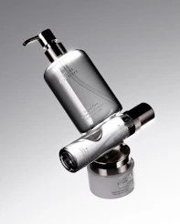 Three silver cosmetic bottles stacked precariously