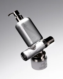 Three silver cosmetic bottles stacked precariously