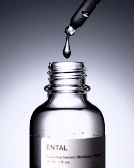 A dropper releases a drop of serum into a bottle.
