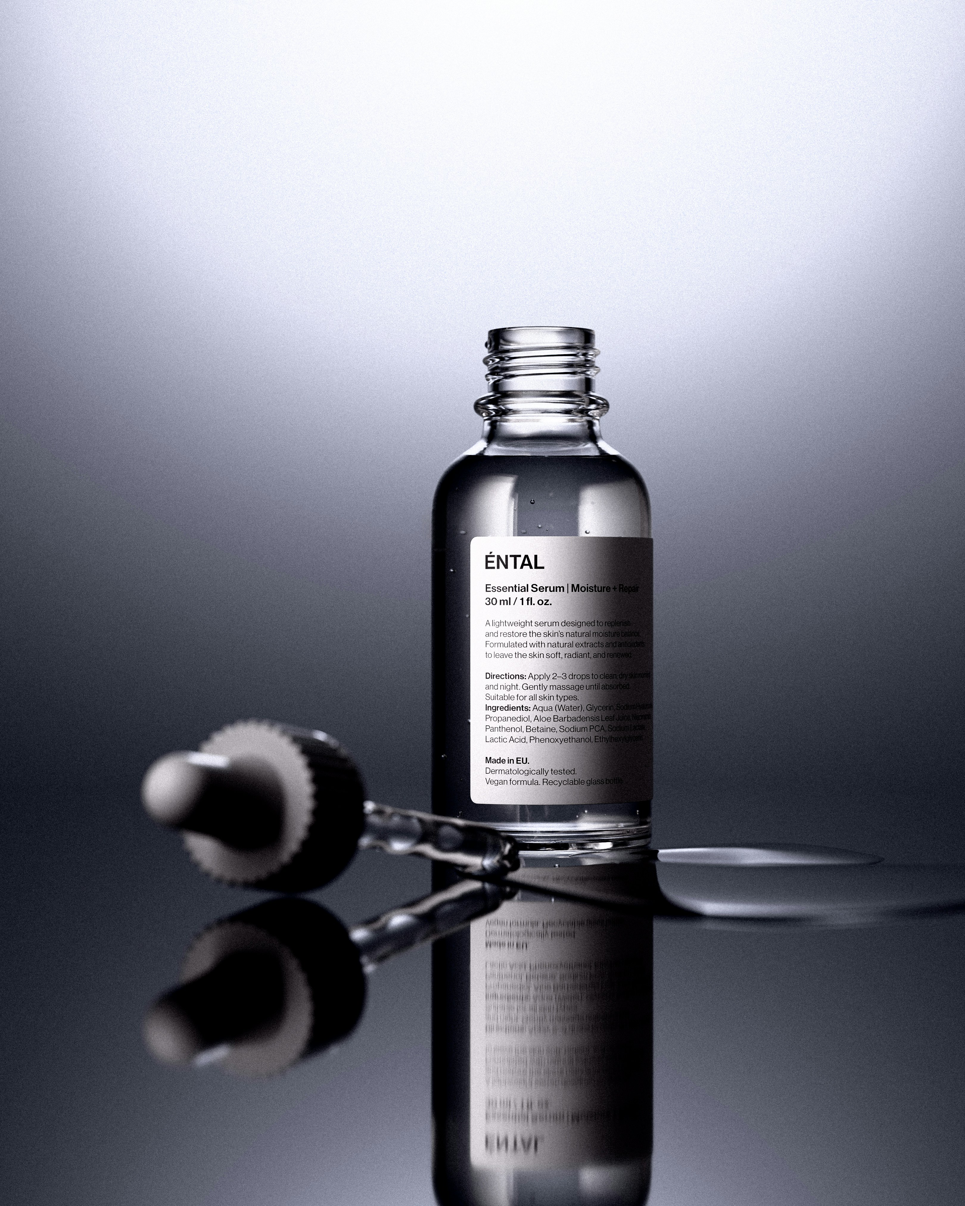 Clear serum bottle with dropper on reflective surface