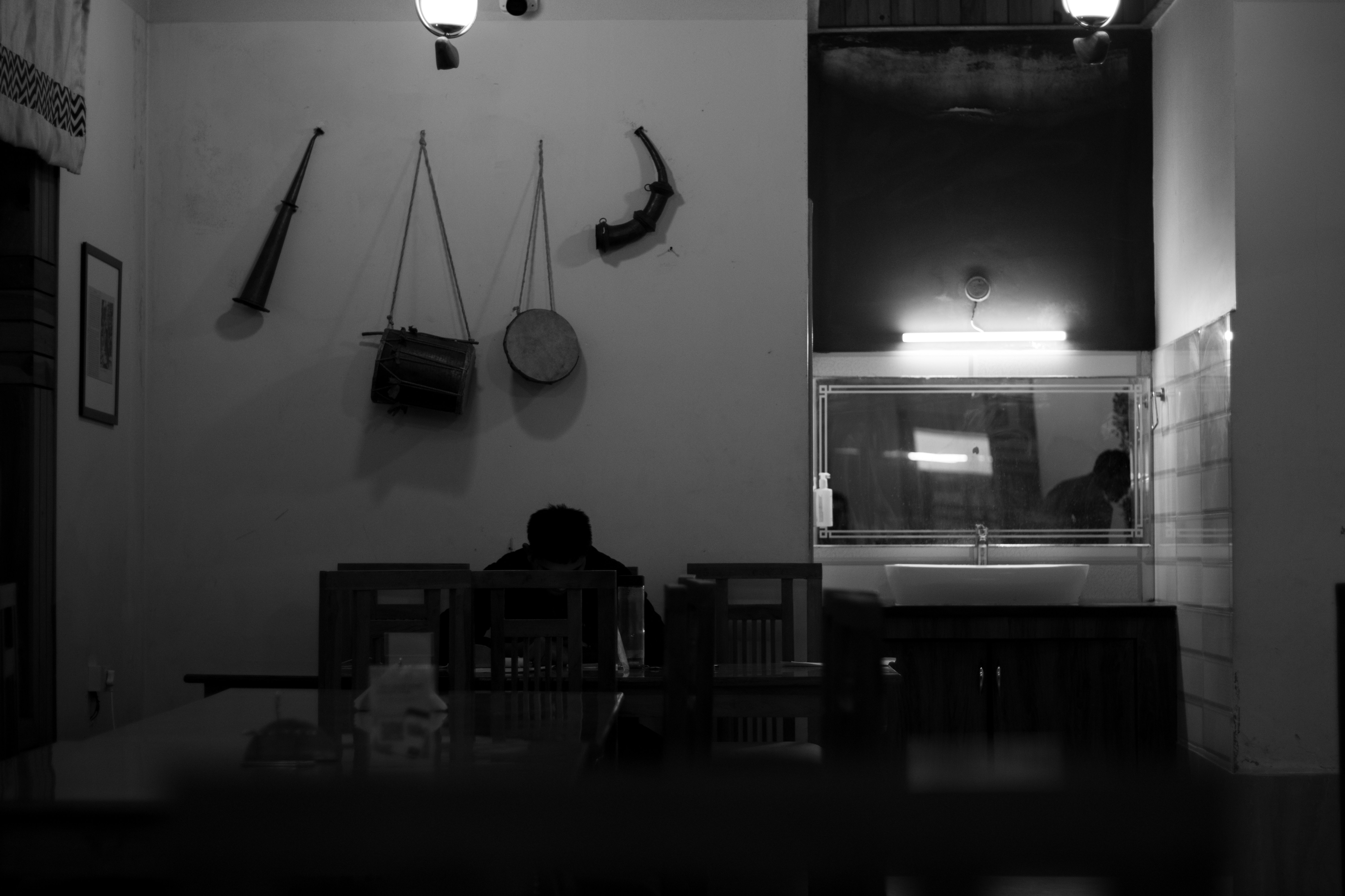Person sitting at table with antique weapons on wall