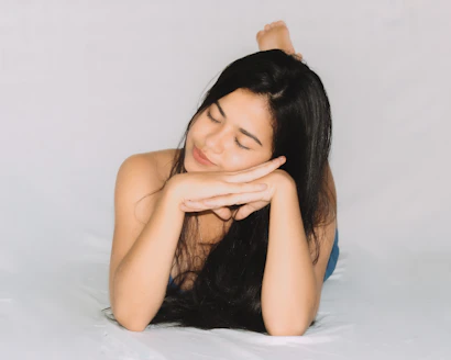 A young woman with long dark hair resting her head