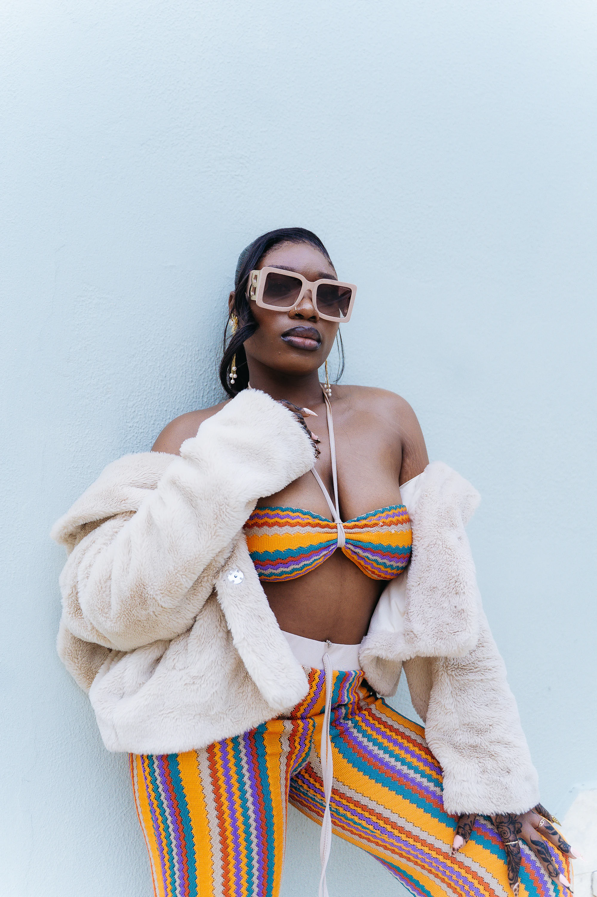 A stylish person wearing bold oversized sunglasses and a colourful outfit