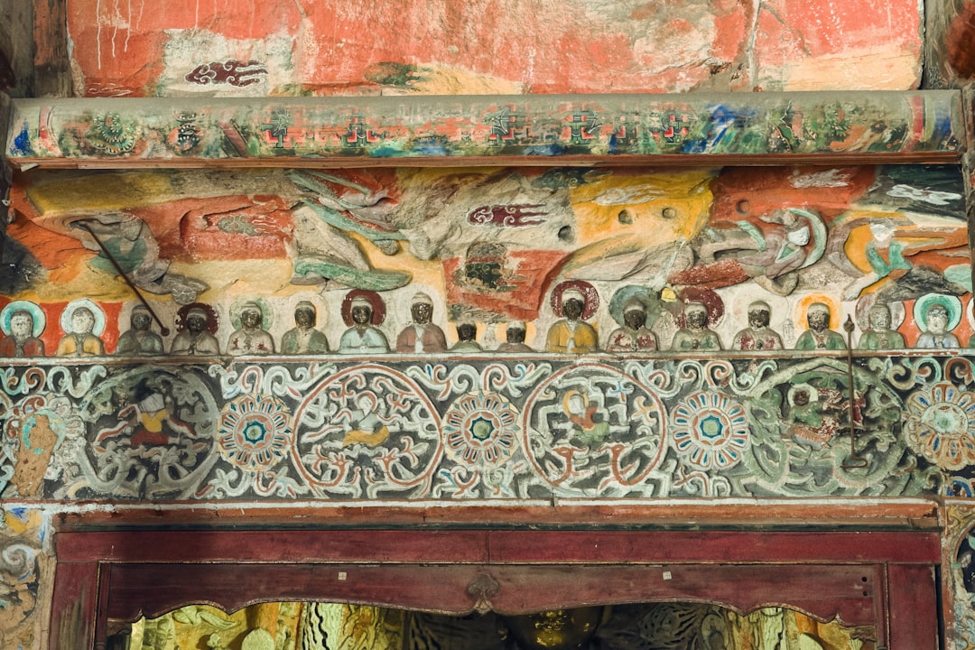 Ancient Buddhist mural artwork showing figures and vibrant colors on temple wall