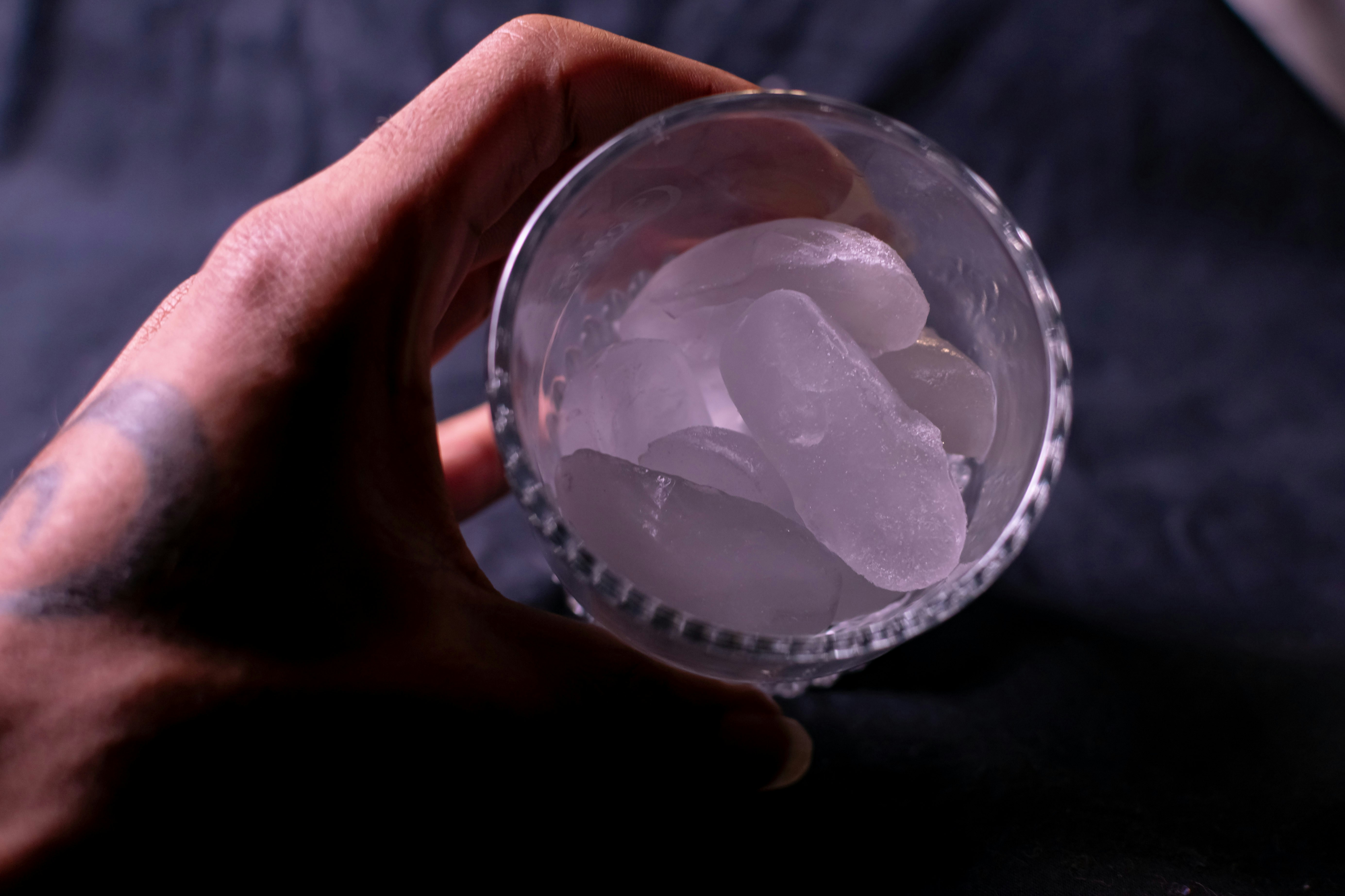 A hand holding a glass of ice cubes