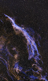 A wispy nebula glows with purple and orange hues.