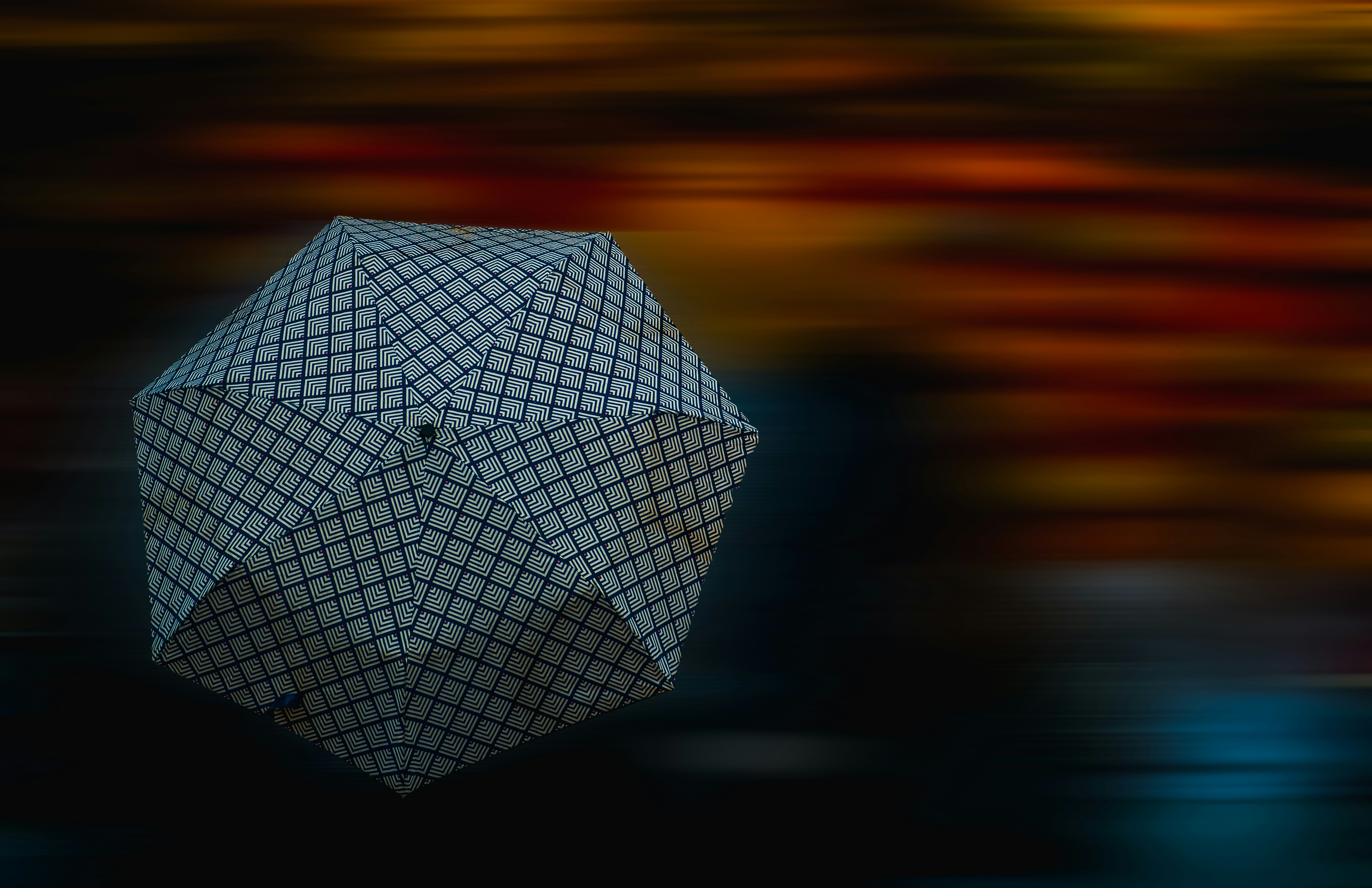 Ein gemusterter Regenschirm vor einem verschwommenen, bunten Hintergrund