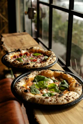 Two fresh pizzas with basil and tomatoes.