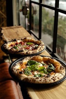 Two fresh pizzas with basil and tomatoes.