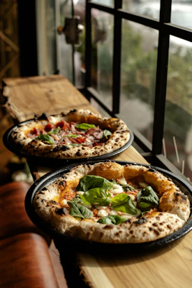 Two fresh pizzas with basil and tomatoes.