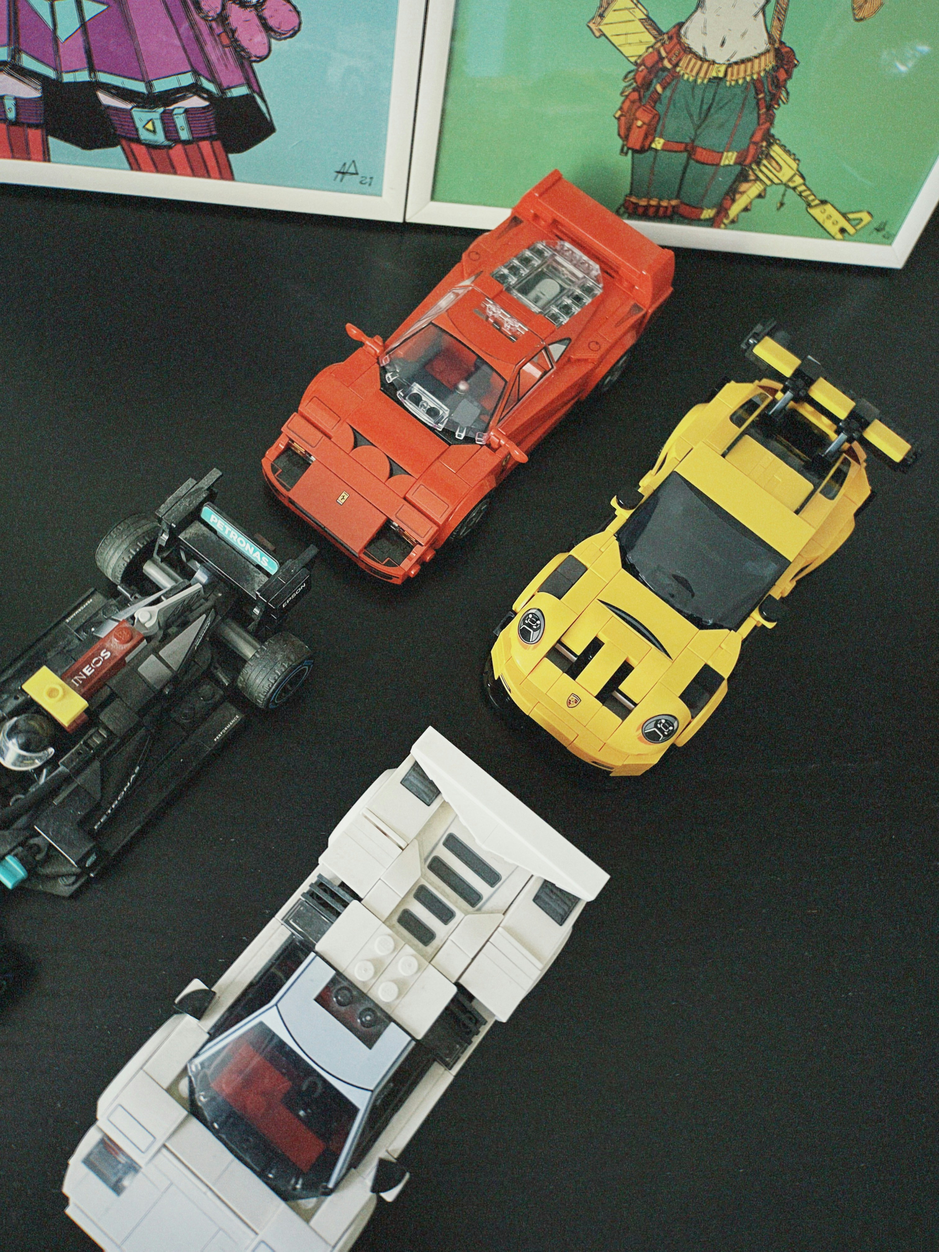 Four toy sports cars on a dark surface.