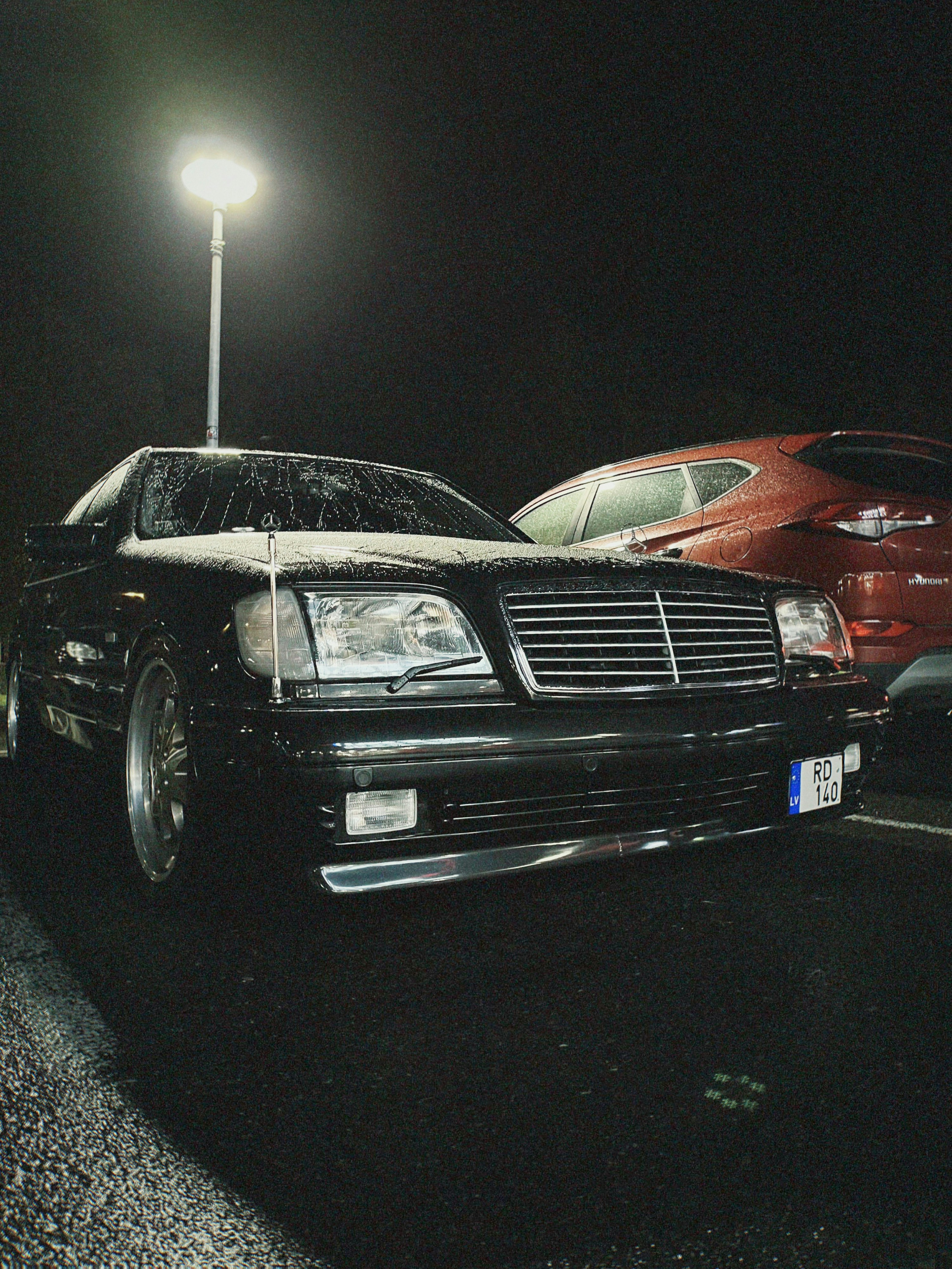 Black car parked under street light at night